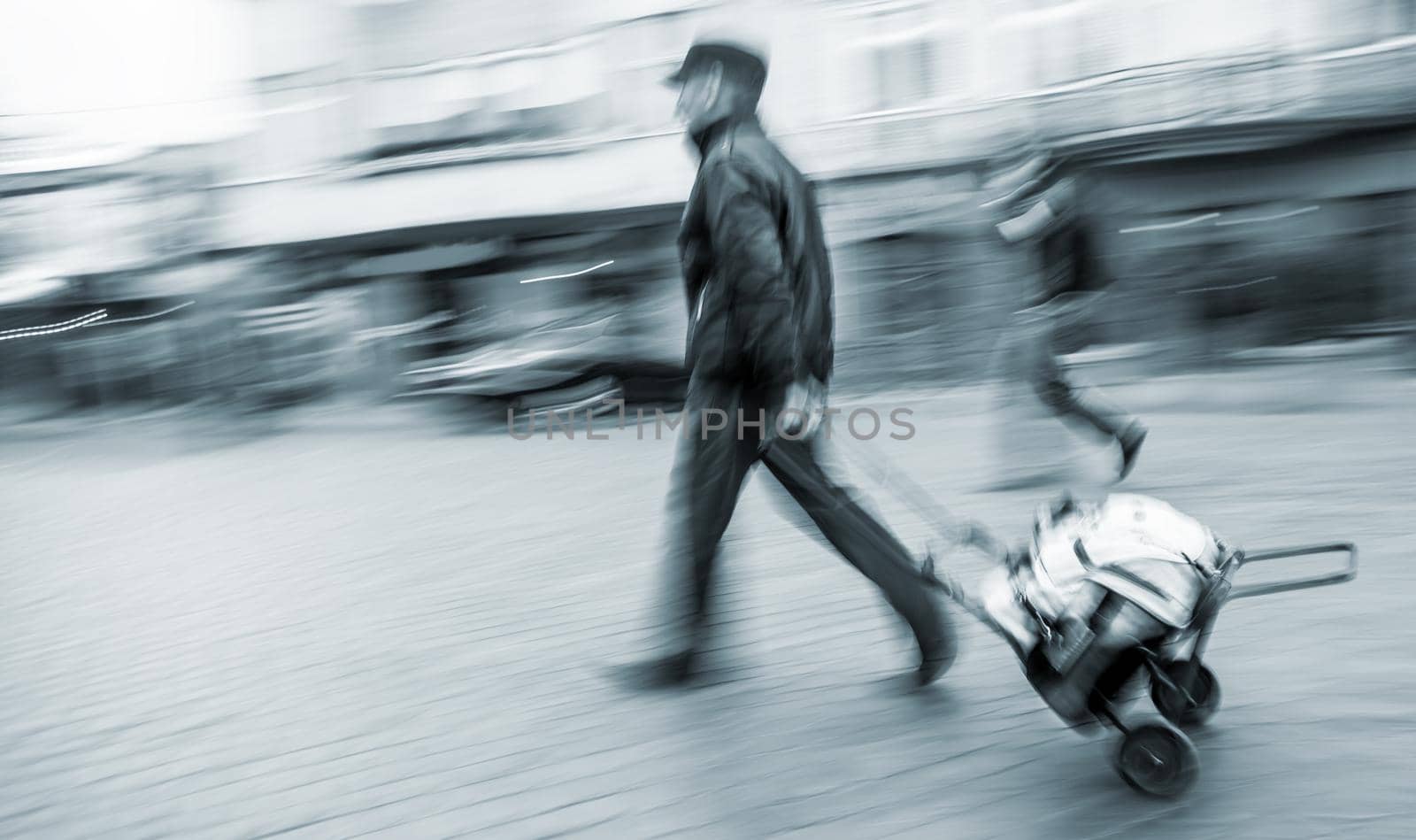 Middle-aged man carries the cart with bag. Intentional motion blur