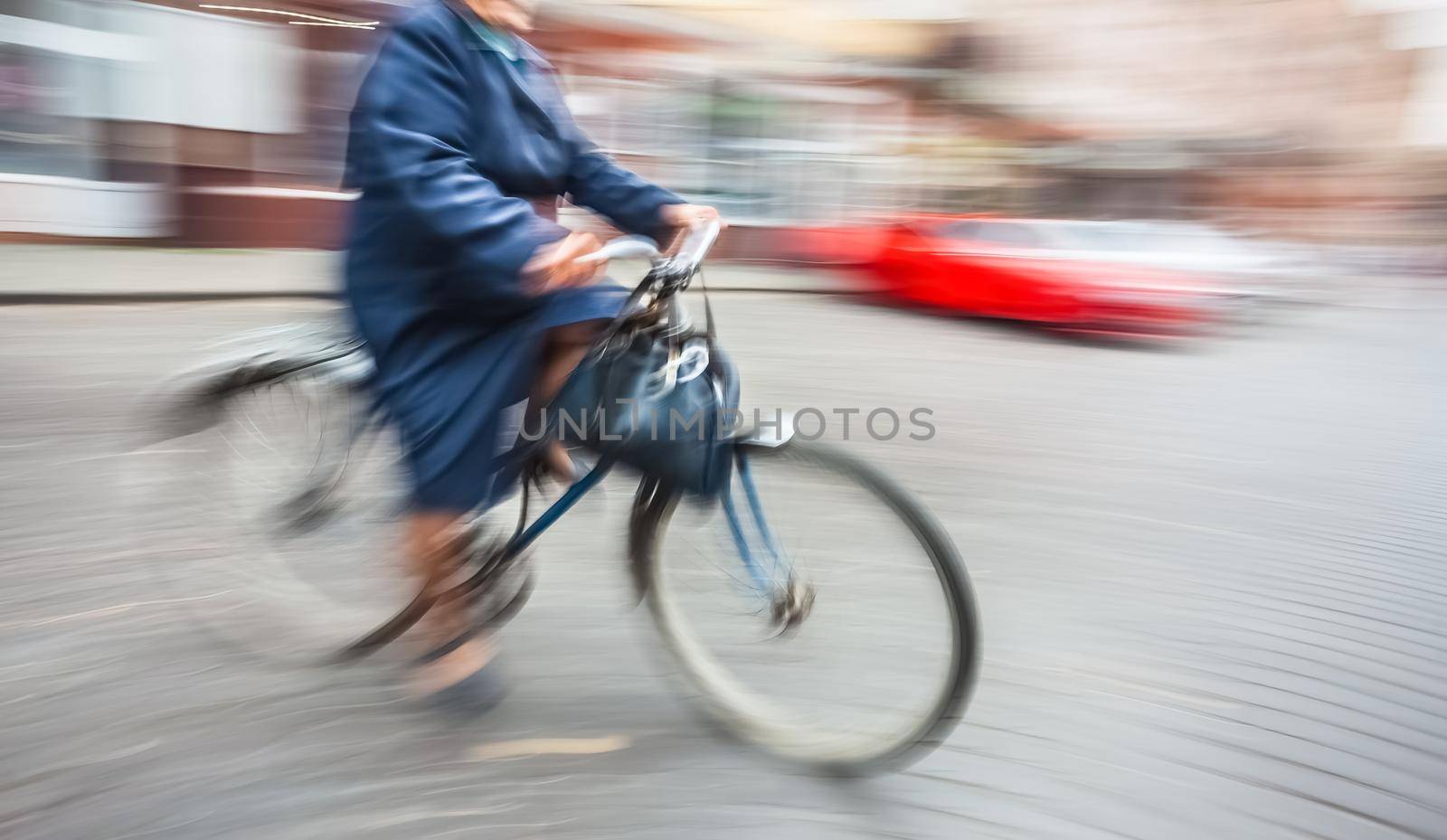 Abstract blurred image of an old woman cyclist on the city roadway. Intentional motion blur