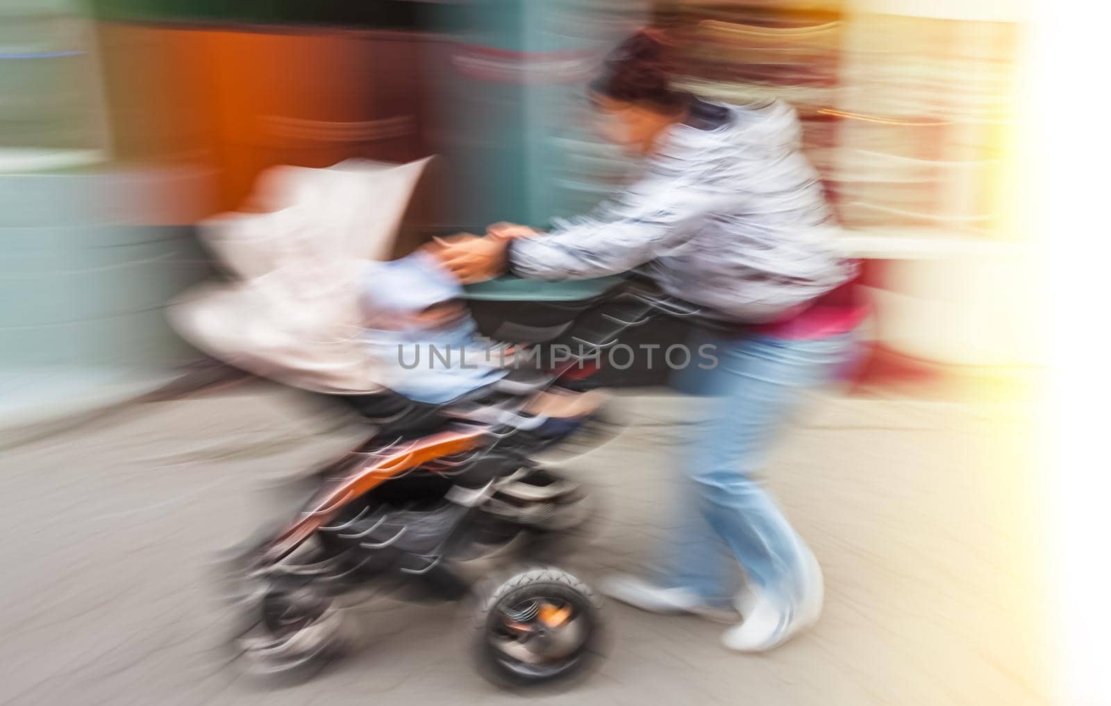 Mother with small children and a pram walking down the street. Intentional motion blur