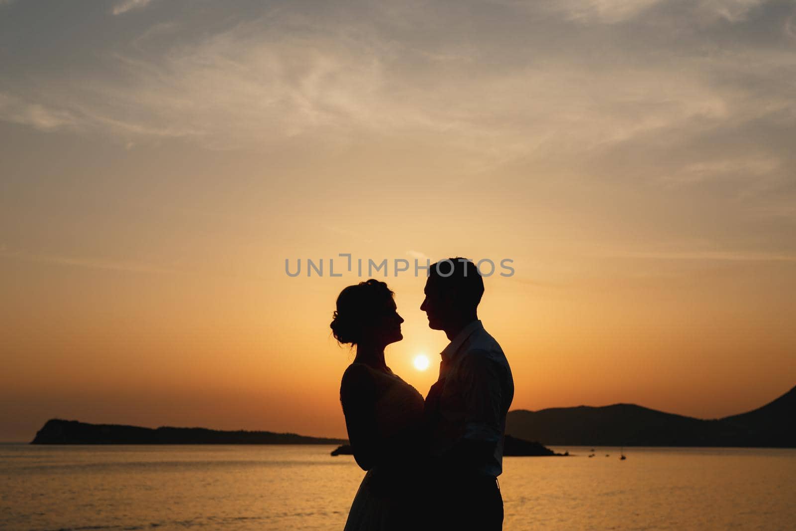 The bride and groom are embracing on the seashore at sunset and look at each other . High quality photo