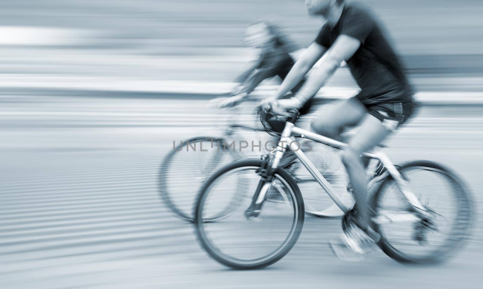 Young man and woman riding bicycles on a city street.  Intentional motion blur