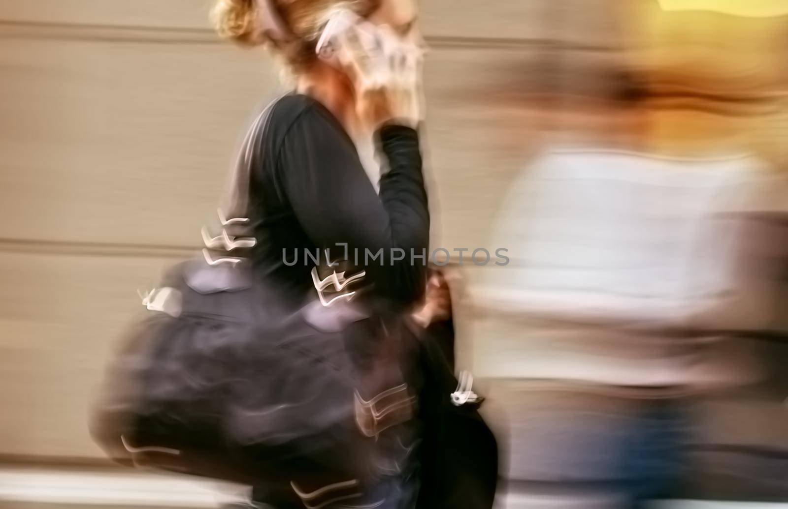Hot day in the city. Woman talking on a cell phone in a hurry. Intentional motion blur and color shift