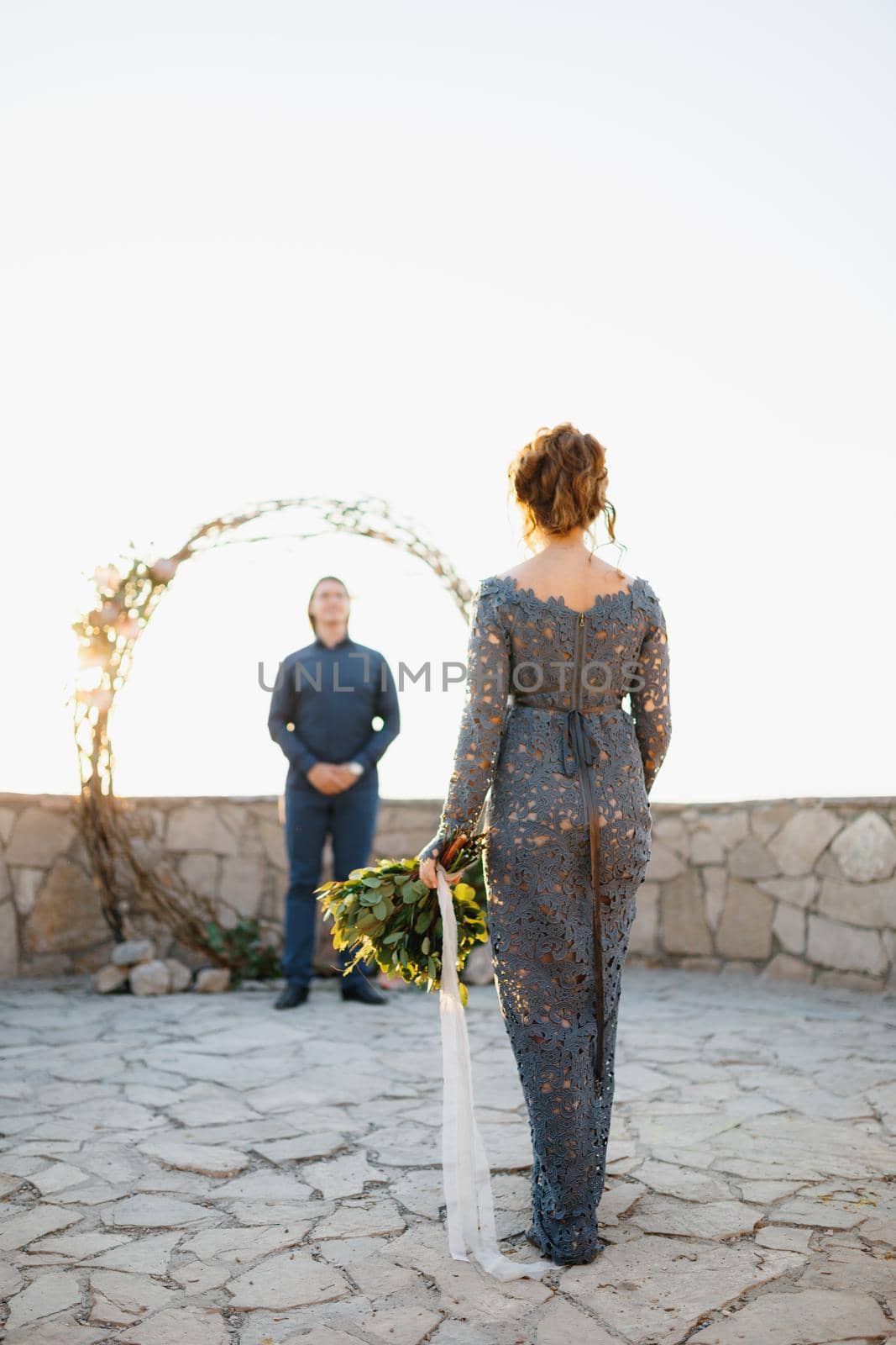A bride with a bouquet in her hand goes to the groom who is waiting for her at the wedding arch . High quality photo