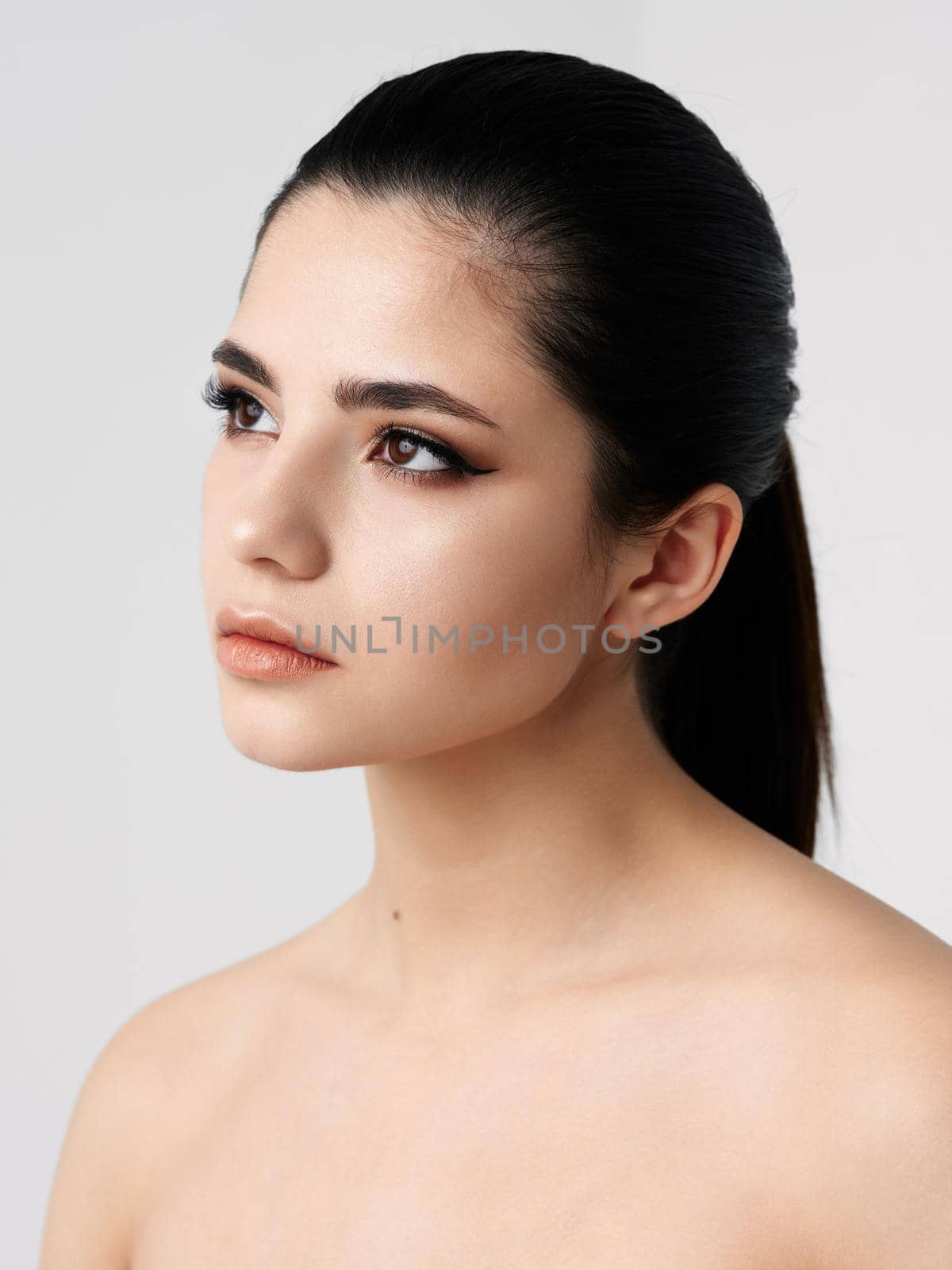 woman looking to the side naked shoulders makeup skin care. High quality photo