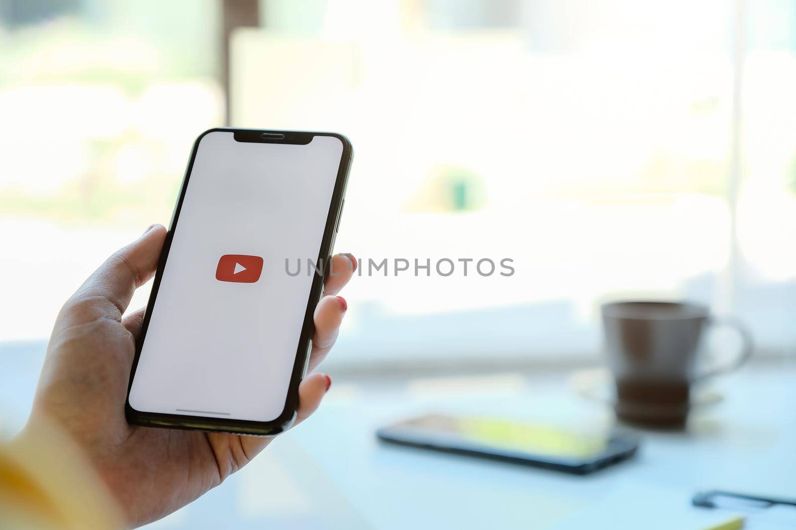 CHIANG MAI, THAILAND - MAR 7 ,2020: Woman holding iPhone Xs with Youtube apps on screen. YouTube is the popular online video sharing website.