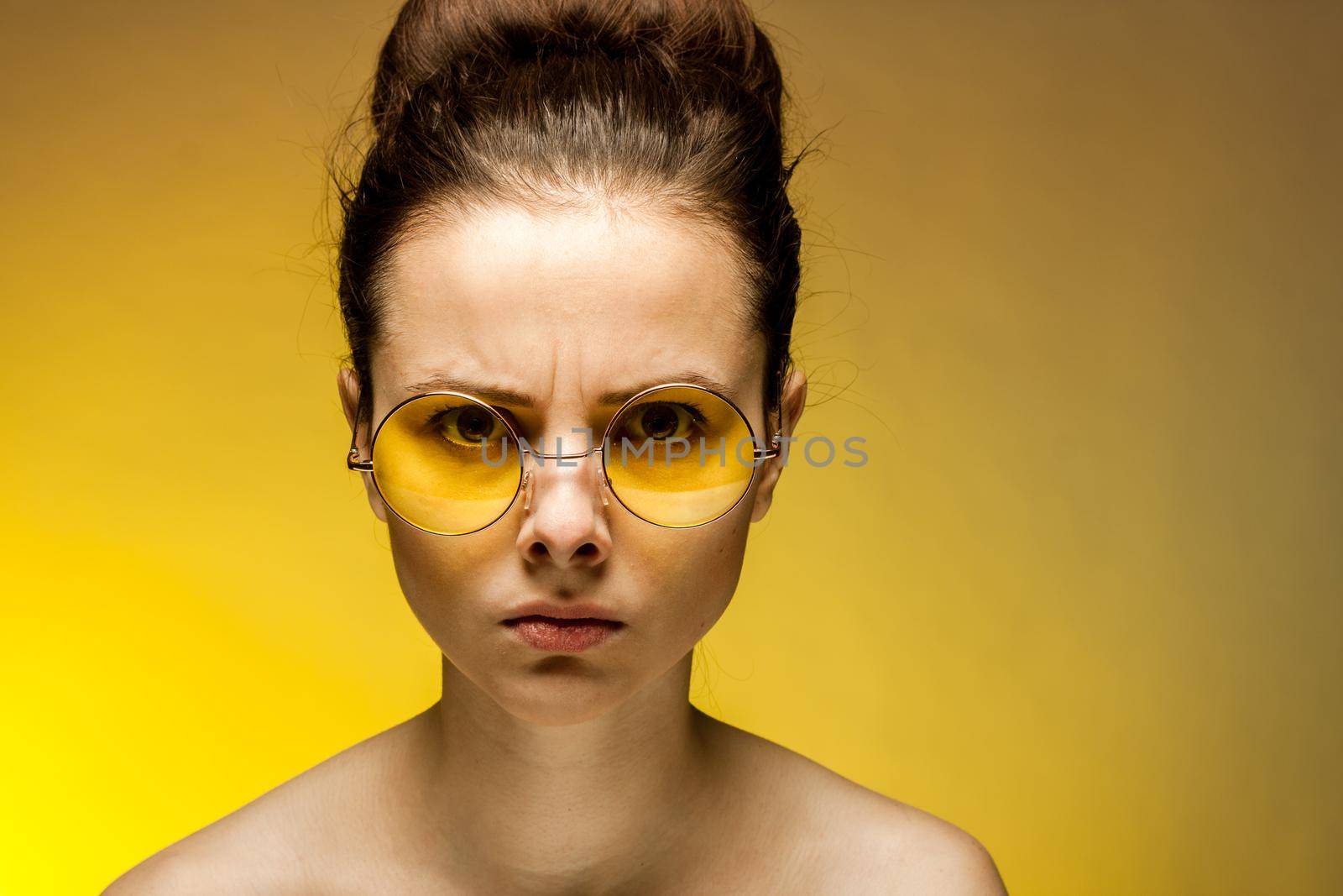 brunette with yellow glasses bare shoulders clear skin emotions. High quality photo
