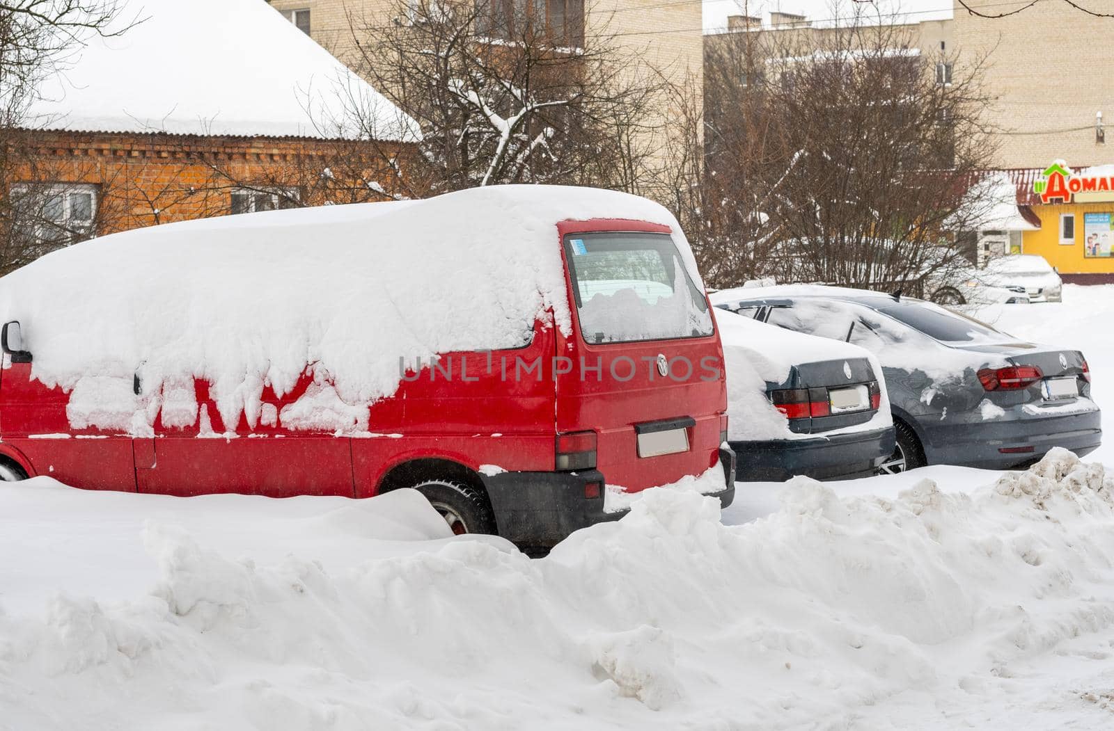 Lutsk, Ukraine - February 12,2020: Stuck car in snow and ice. City street after blizzard. Buried vehicle in snowdrift. Parking in winter after snowfall. Uncleaned road. Record-breaking amounts of snow