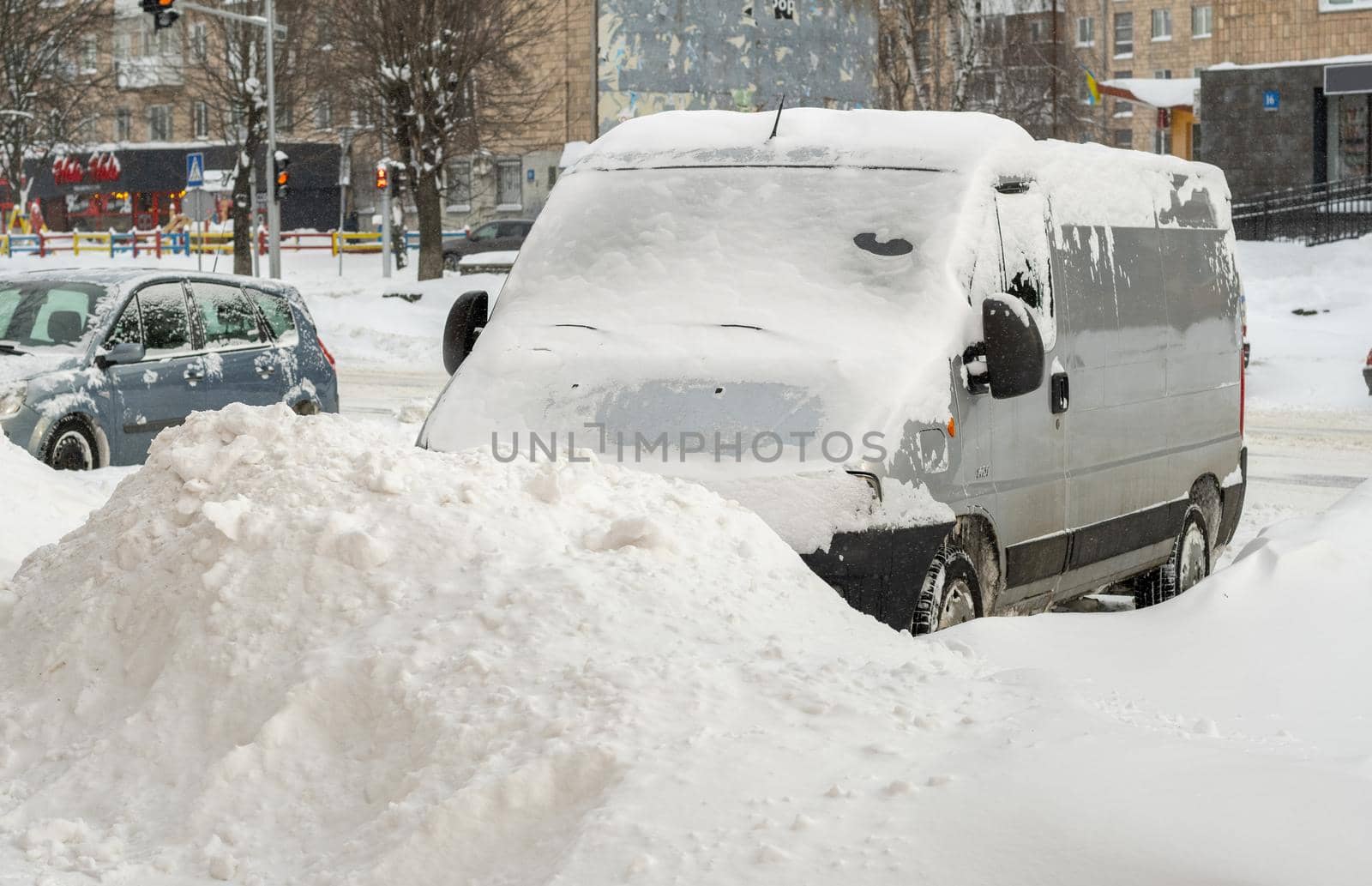 Lutsk, Ukraine - February 12,2020: Stuck car in snow and ice. City street after blizzard. Buried vehicle in snowdrift. Parking in winter after snowfall. Uncleaned road. Record-breaking amounts of snow