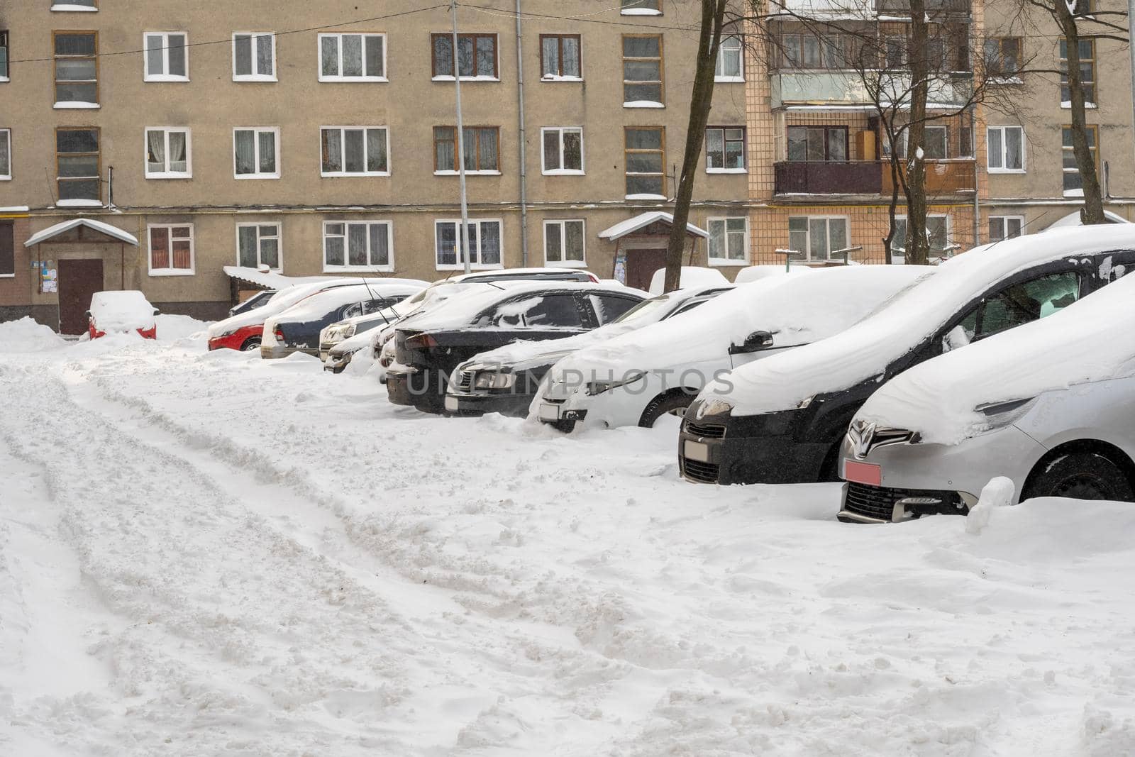Lutsk, Ukraine - February 12,2020: Stuck car in snow and ice. City street after blizzard. Buried vehicle in snowdrift. Parking in winter after snowfall. Uncleaned road. Record-breaking amounts of snow