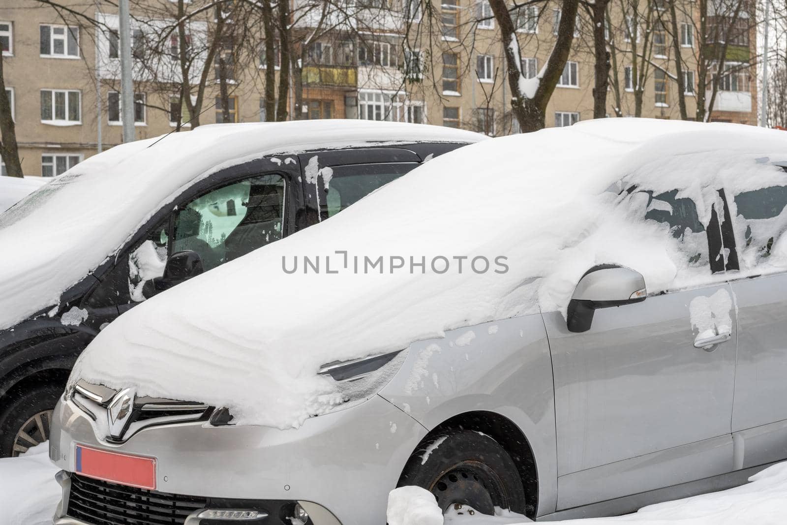 Lutsk, Ukraine - February 12,2020: Stuck car in snow and ice. City street after blizzard. Buried vehicle in snowdrift. Parking in winter after snowfall. Uncleaned road. Record-breaking amounts of snow