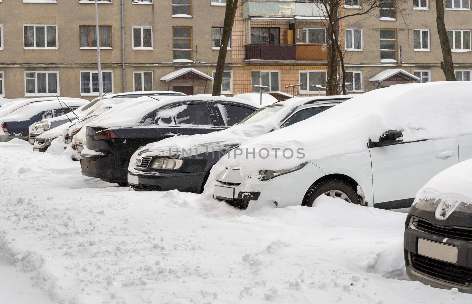 Lutsk, Ukraine - February 12,2020: Stuck car in snow and ice. City street after blizzard. Buried vehicle in snowdrift. Parking in winter after snowfall. Uncleaned road. Record-breaking amounts of snow