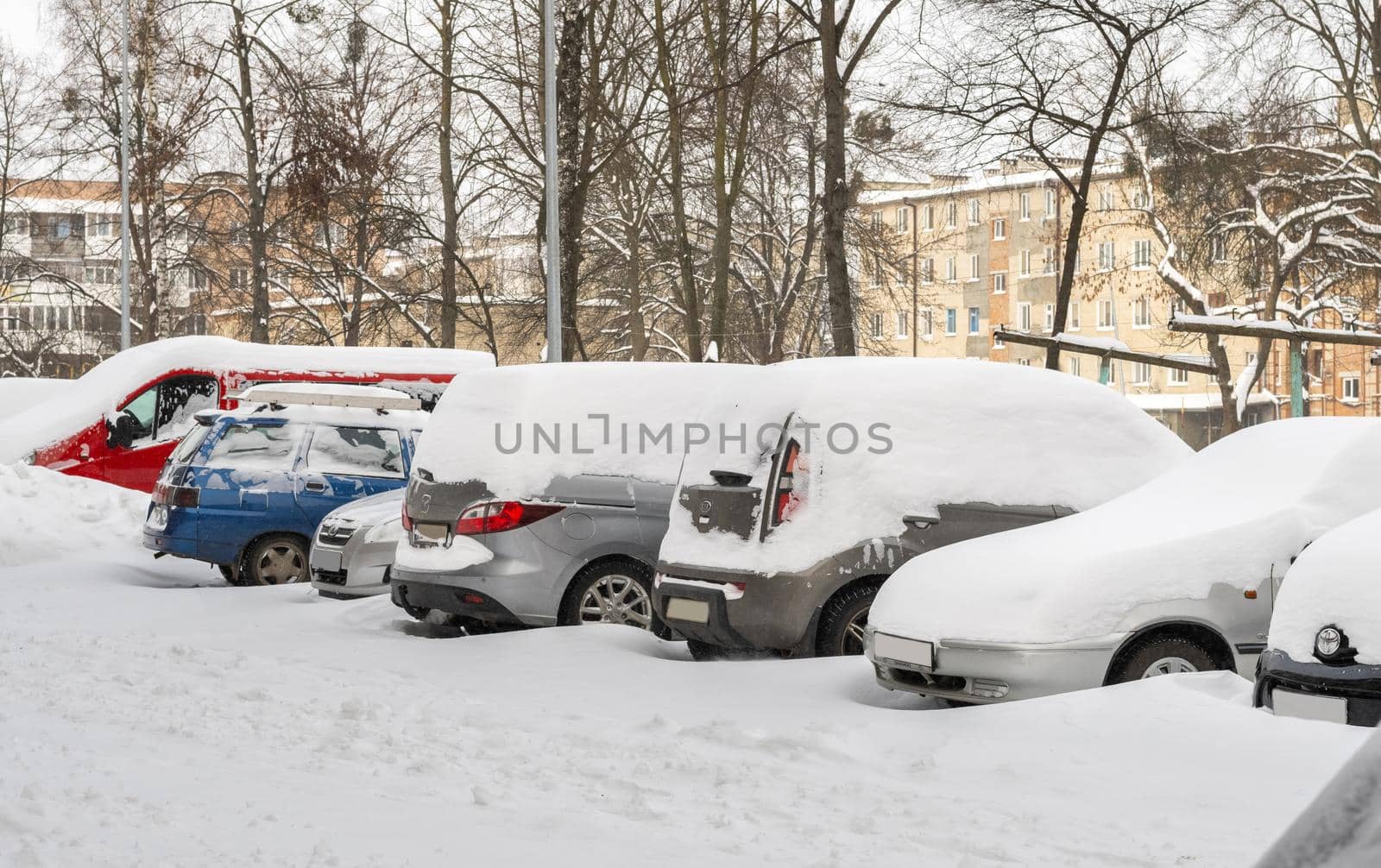 Lutsk, Ukraine - February 12,2020: Stuck car in snow and ice. City street after blizzard. Buried vehicle in snowdrift. Parking in winter after snowfall. Uncleaned road. Record-breaking amounts of snow