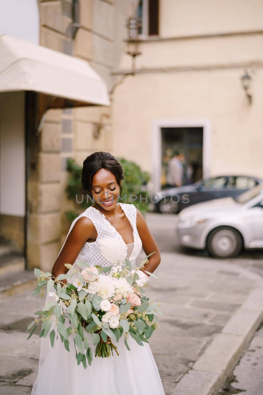 African-American bride in white dress and long veil. With a lush bouquet of the bride in her hands. Wedding in Florence, Italy.
