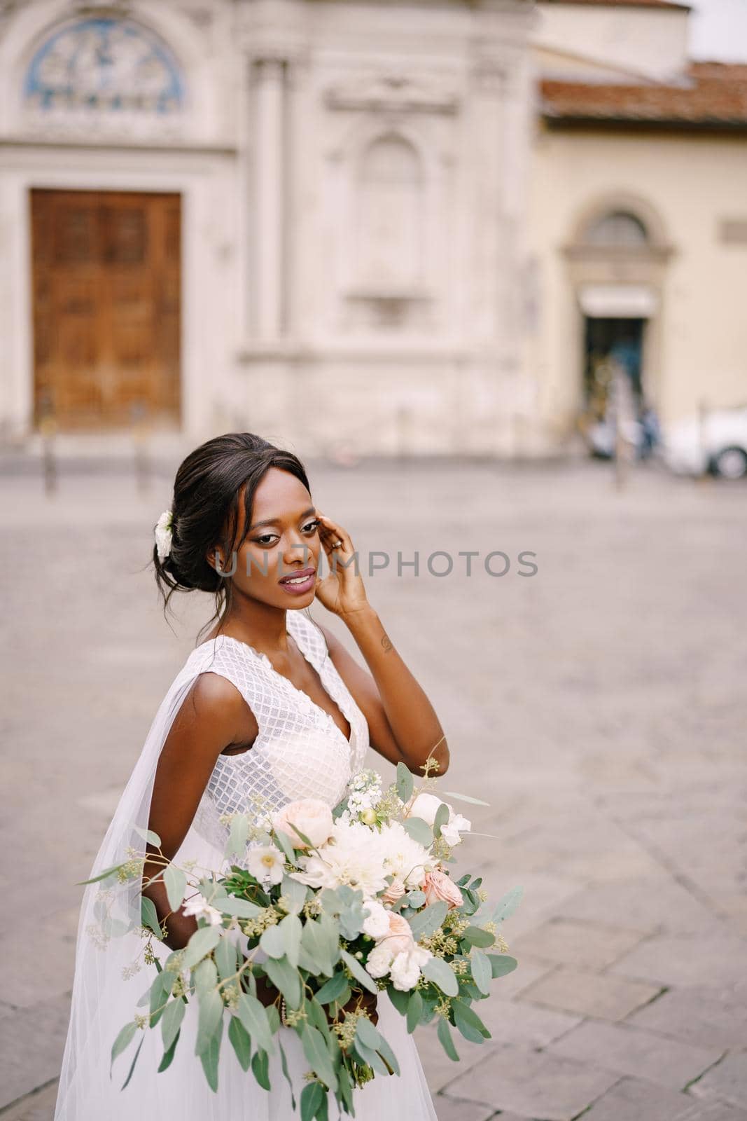 African-American bride in white dress and long veil. With a lush bouquet of the bride in her hands. Wedding in Florence, Italy.