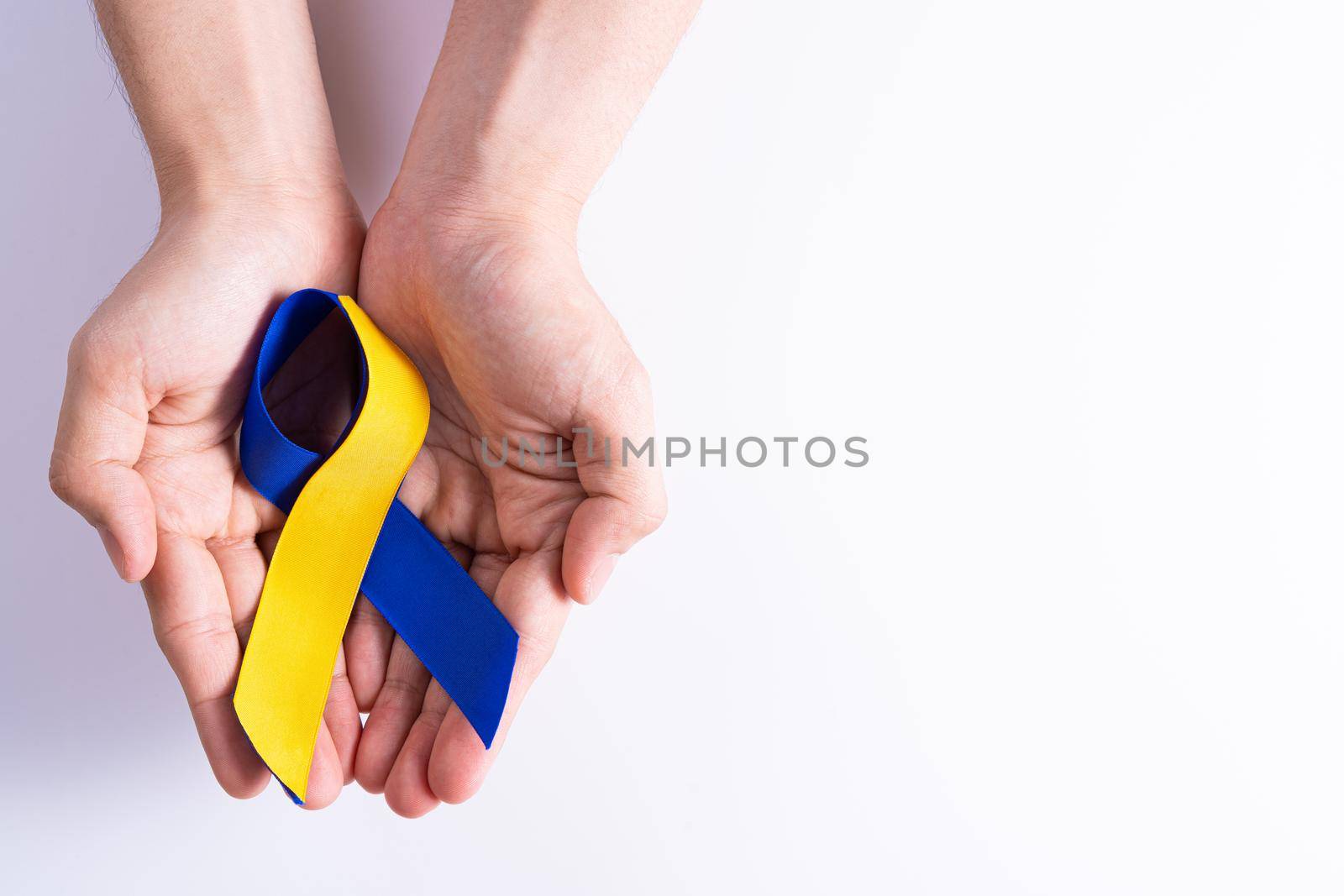 Down syndrome day, hands holding blue yellow ribbon awareness support patient with illness disability