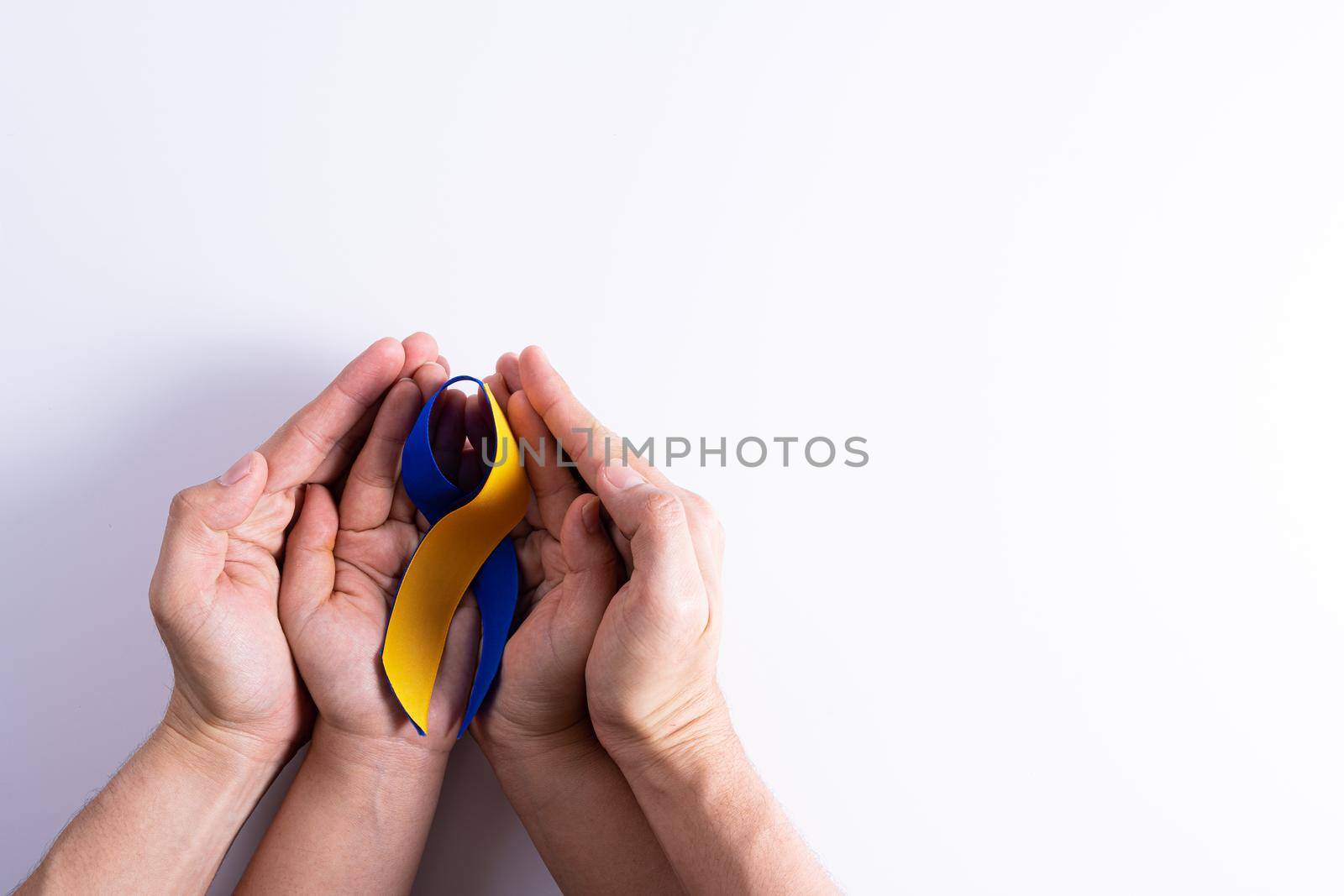 Down syndrome day, man and woman hands holding blue yellow ribbon awareness support patient with illness disability