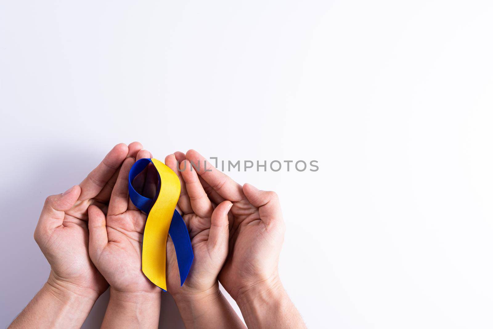 Down syndrome day, man and woman hands holding blue yellow ribbon awareness support patient with illness disability