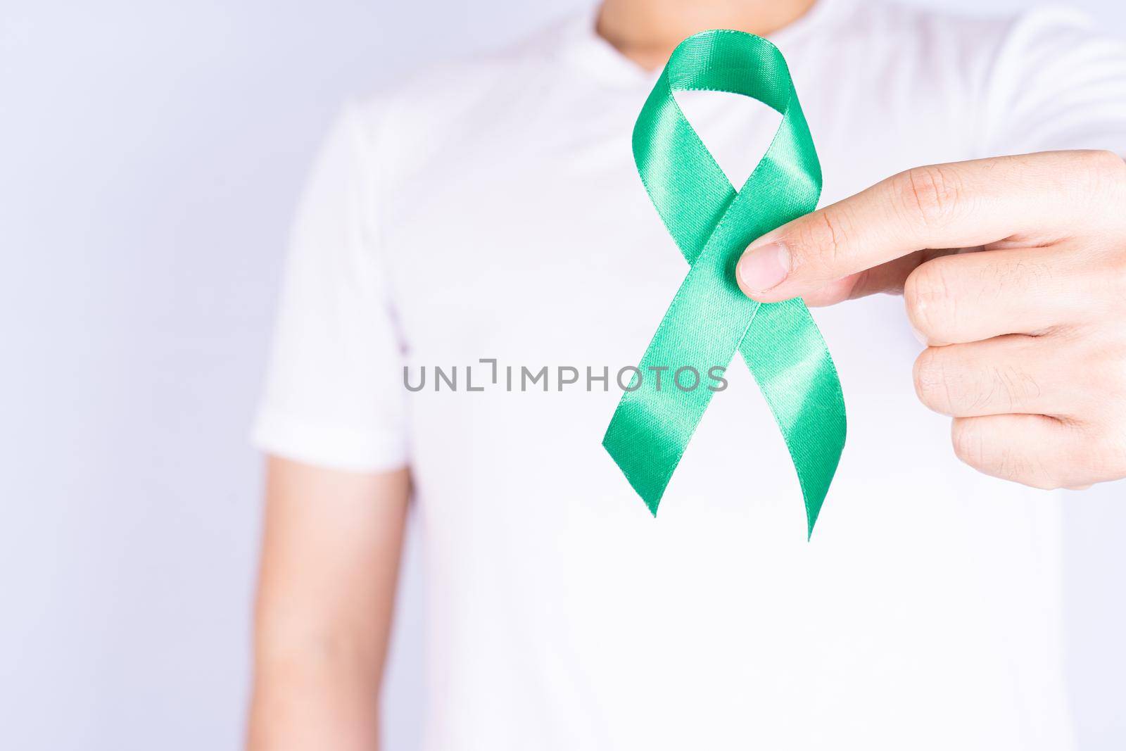 World kidney day, hands holding green ribbon awareness of kidney disease on chest isolated grey background.