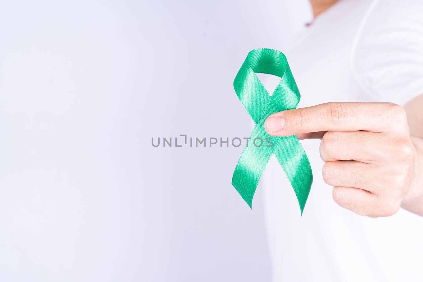 World kidney day, hands holding green ribbon awareness of kidney disease on chest isolated grey background.