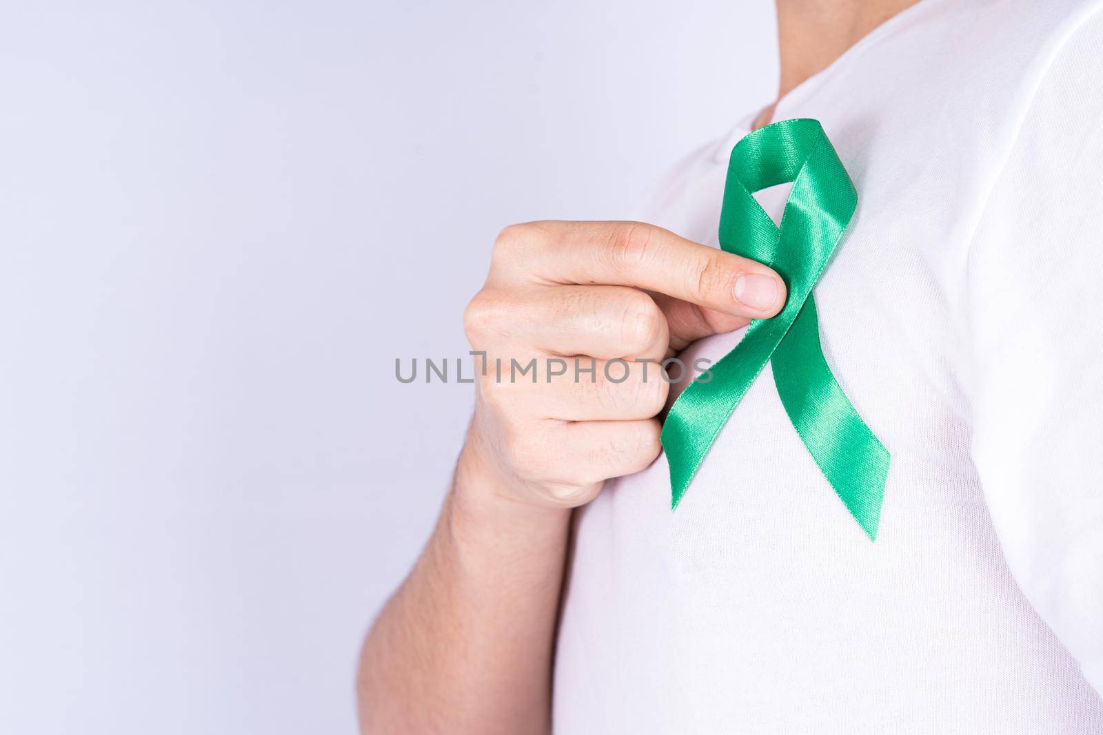 World kidney day, hands holding green ribbon awareness of kidney disease on chest isolated grey background. by mikesaran