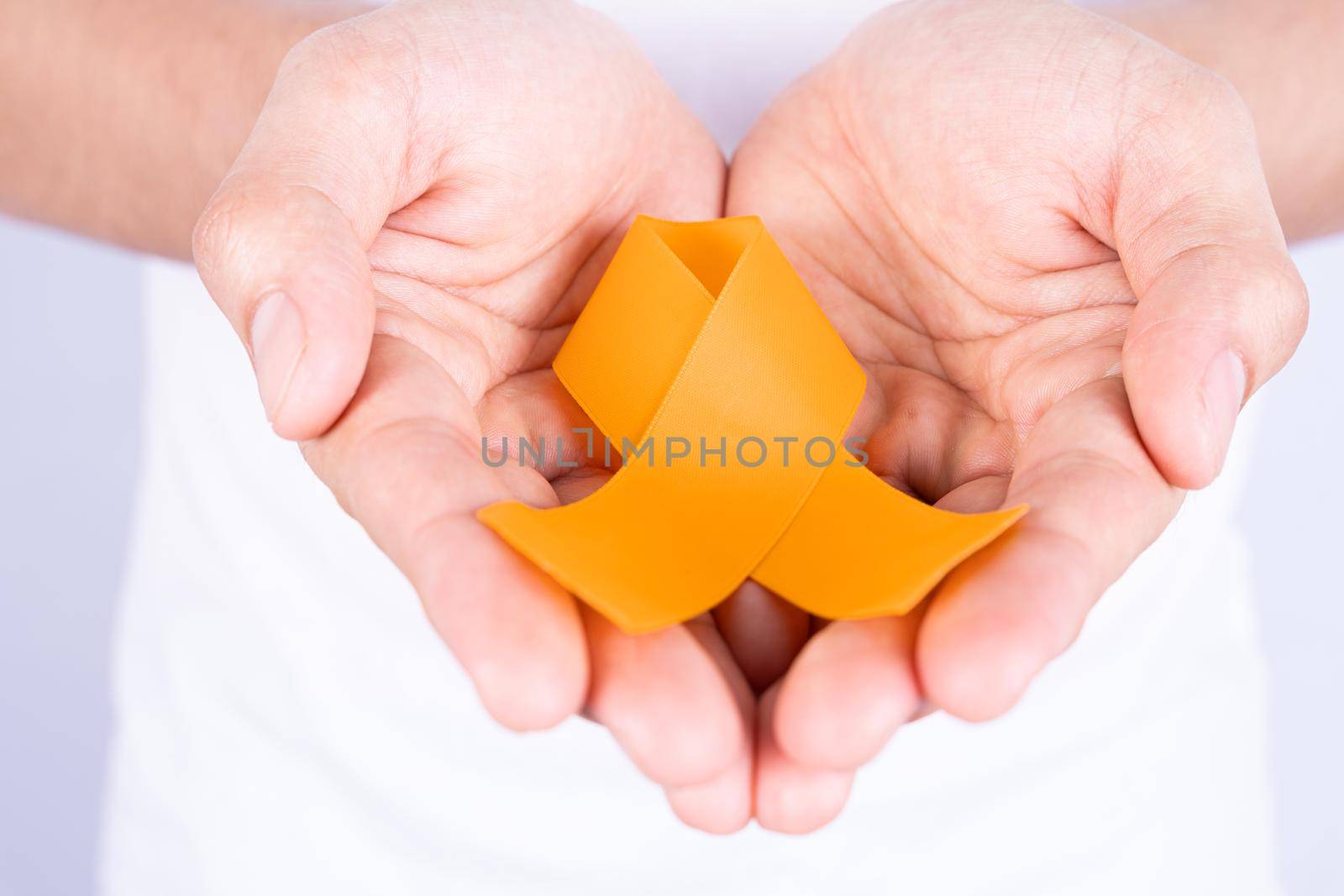 World kidney day, hands holding orange ribbon awareness of kidney disease isolated white background.