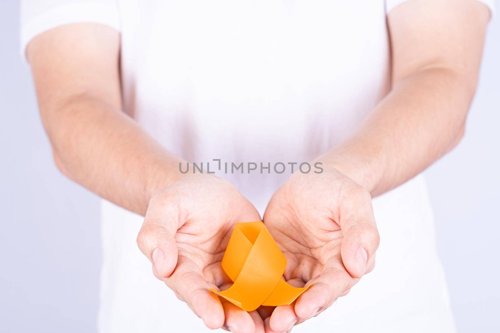 World kidney day, hands holding orange ribbon awareness of kidney disease isolated white background.