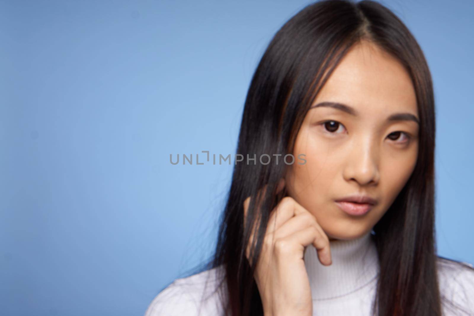 pretty woman asian cosmetology white sweater blue background dark hair. High quality photo