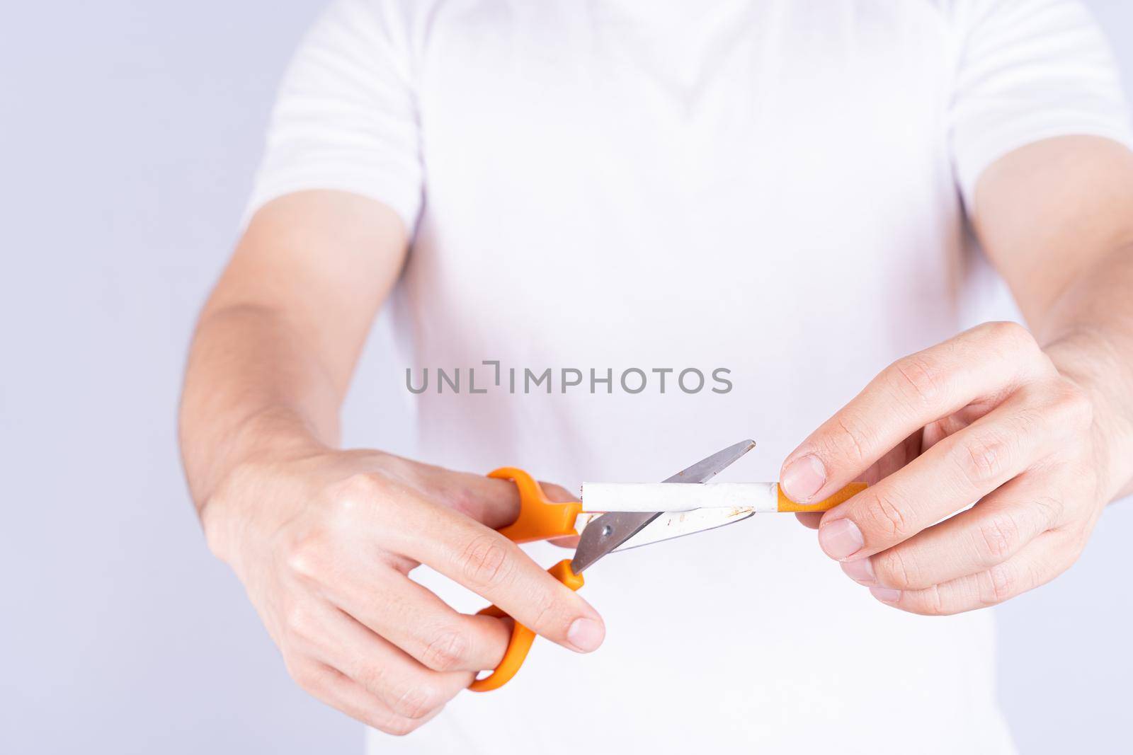 Male hand using scissors cutting cigarette. World no Tobacco and stop smoking day. by mikesaran