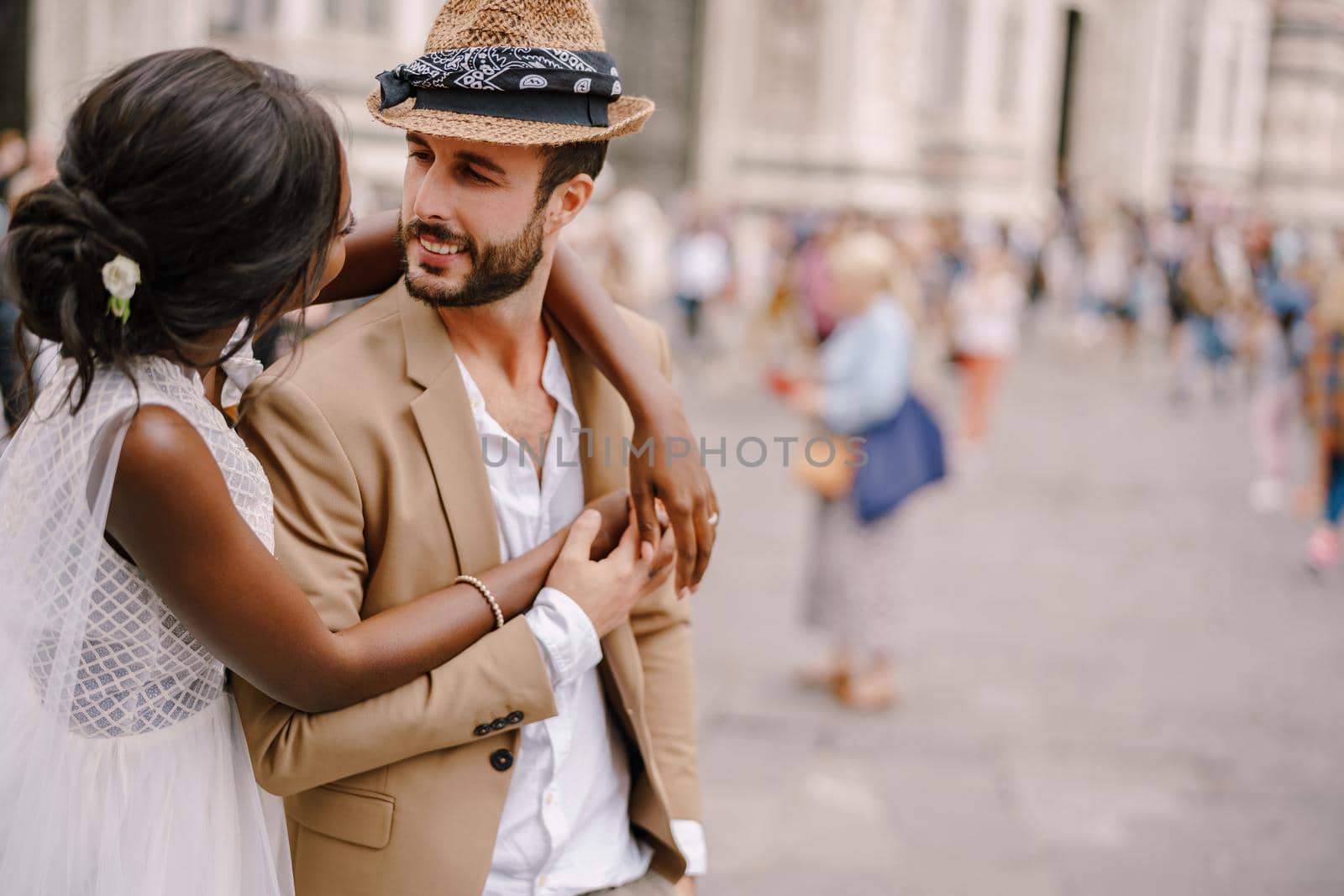 Interracial wedding couple. Wedding in Florence, Italy. African-American bride hugs from behind a Caucasian groom. by Nadtochiy
