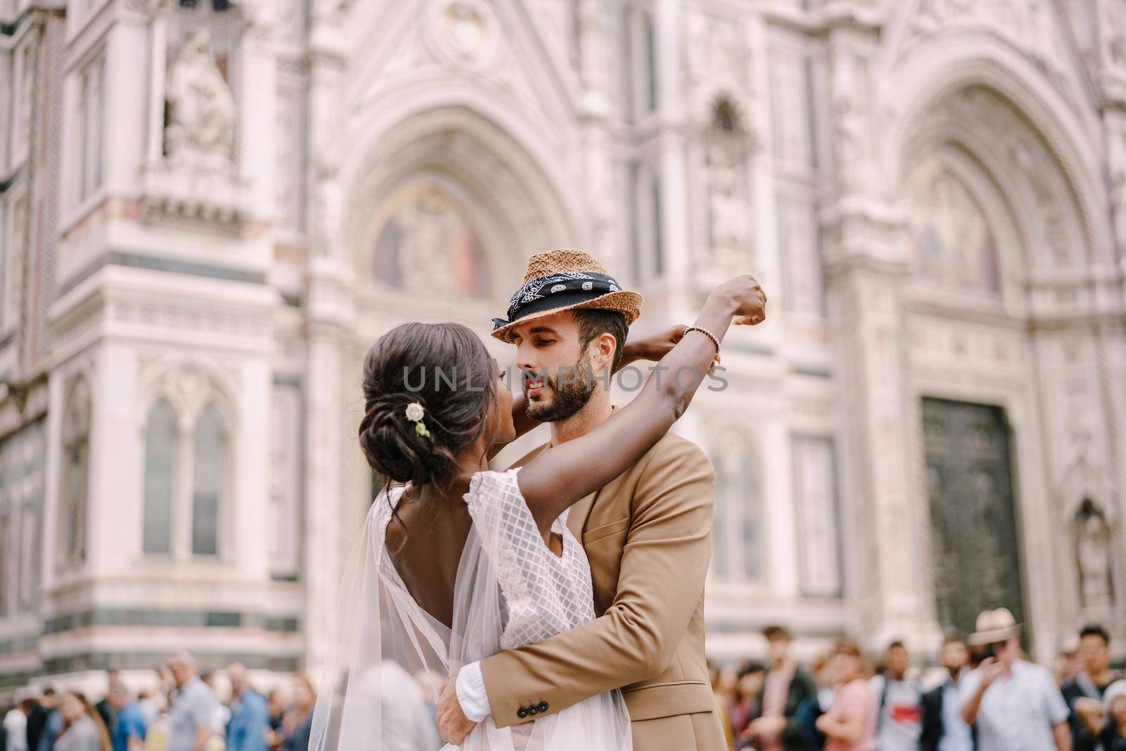 African-American bride and Caucasian groom cuddling in Piazza del Duomo. Wedding in Florence, Italy. Interracial wedding couple