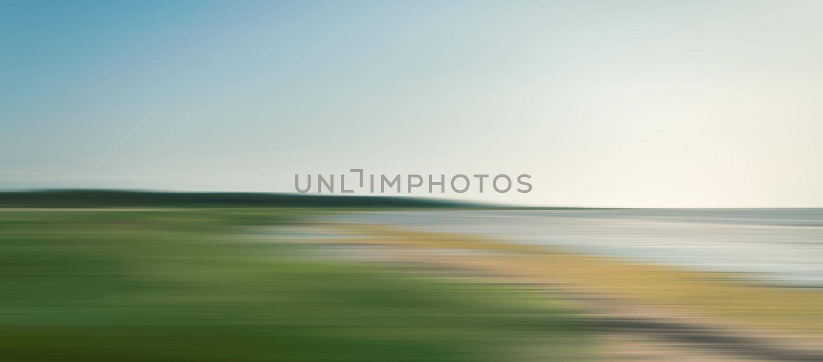 Abstract blurred sea landscape with grass on the beach and blue sky