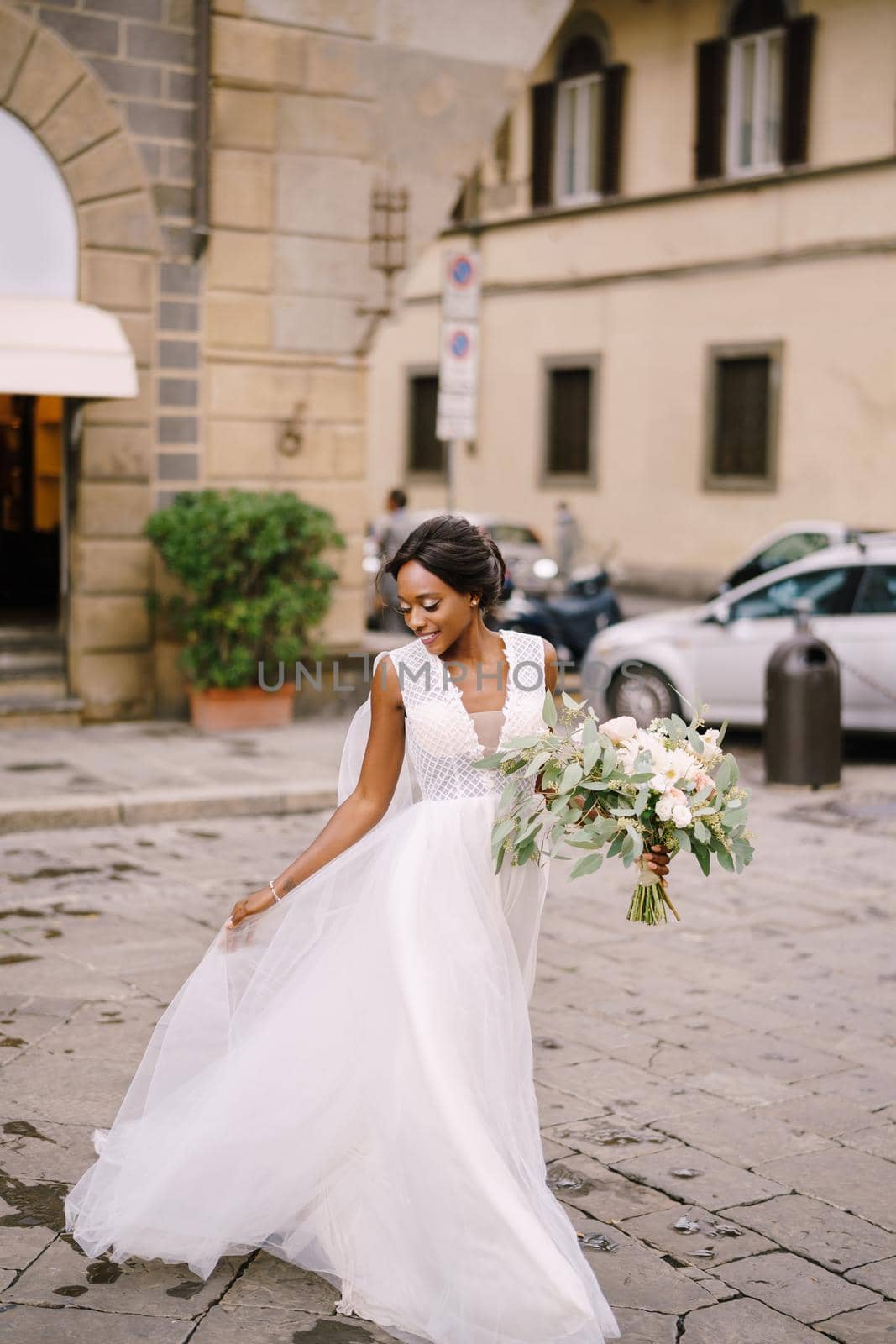 African-American bride in a white dress with a long veil and bouquet in hand. Wedding in Florence, Italy.
