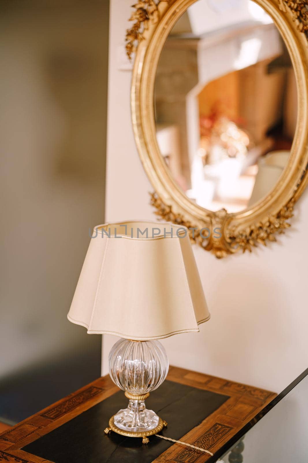 Vintage vintage table lamp with white lampshade and crystal base. An old mirror in a golden frame.