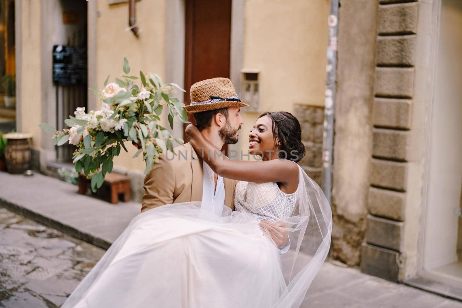 Interracial wedding couple. Wedding in Florence, Italy. Caucasian groom circling African-American bride. by Nadtochiy