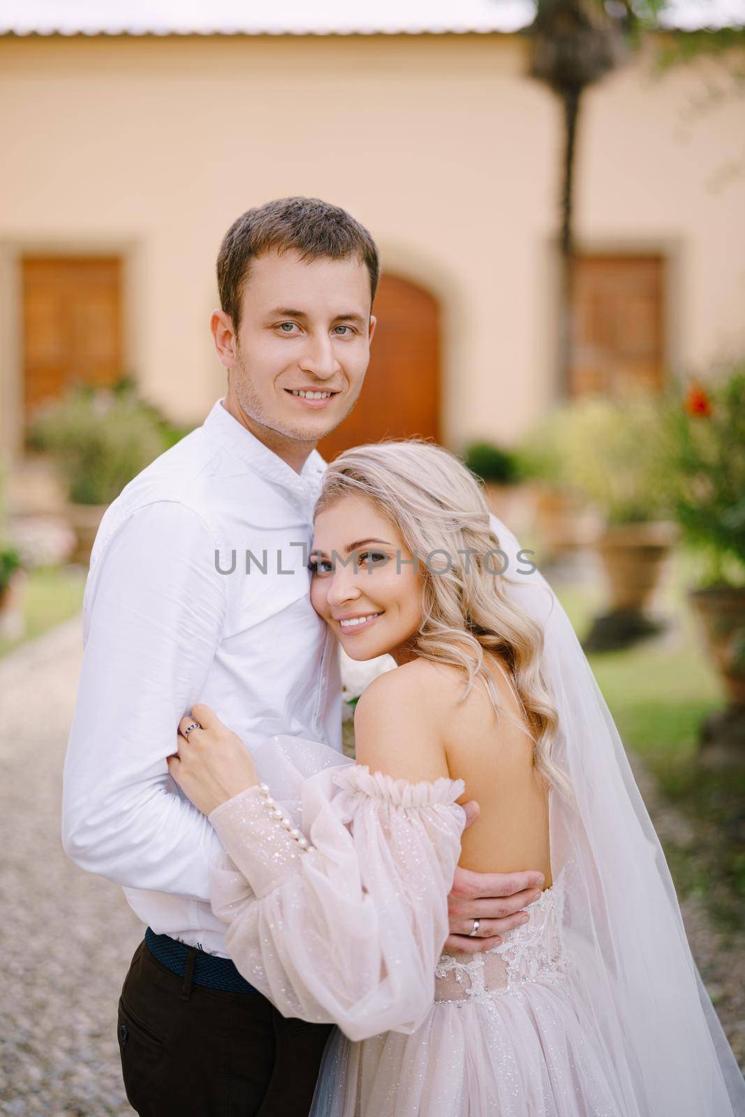 Wedding in Florence, Italy, in an old villa-winery. The young couple cuddles and looks into the camera.