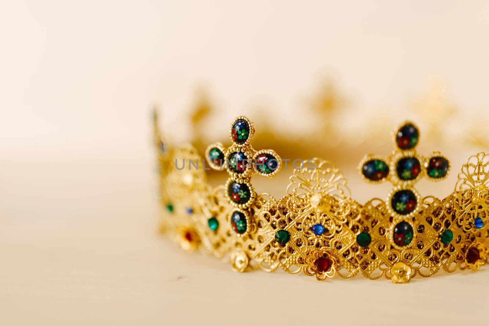 Golden crown encrusted with precious stones and crosses against a white background
