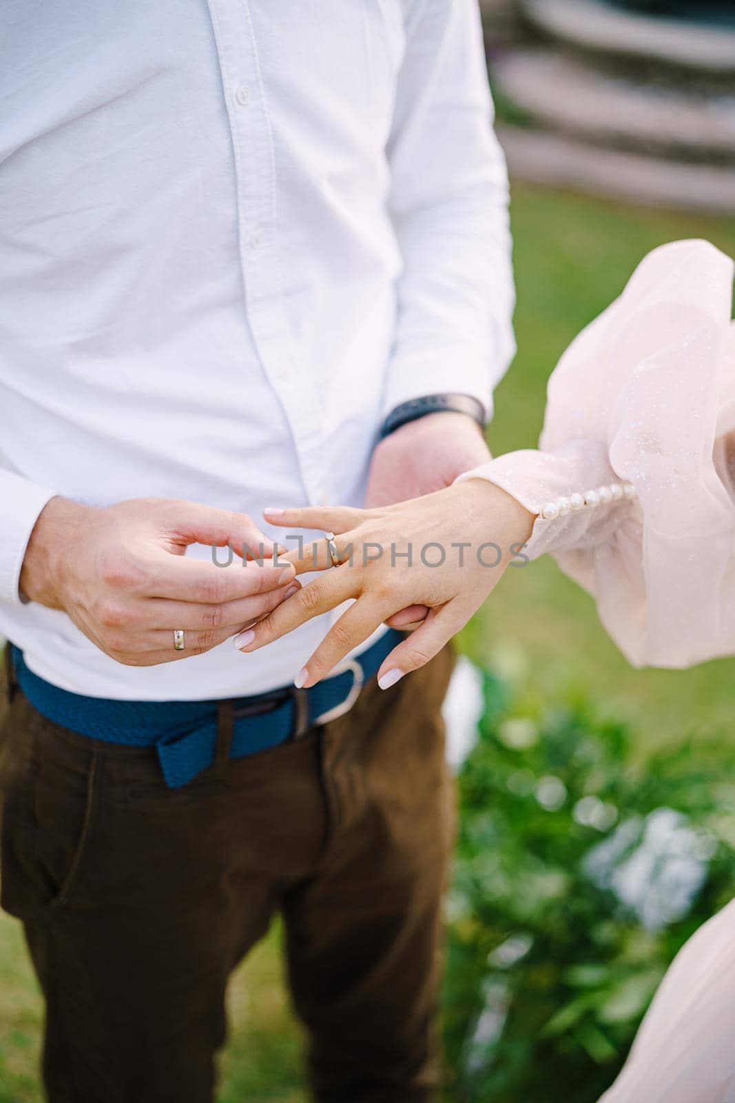Wedding at an old winery villa in Tuscany, Italy. The groom puts the wedding ring on the brides finger, close-up of hands.