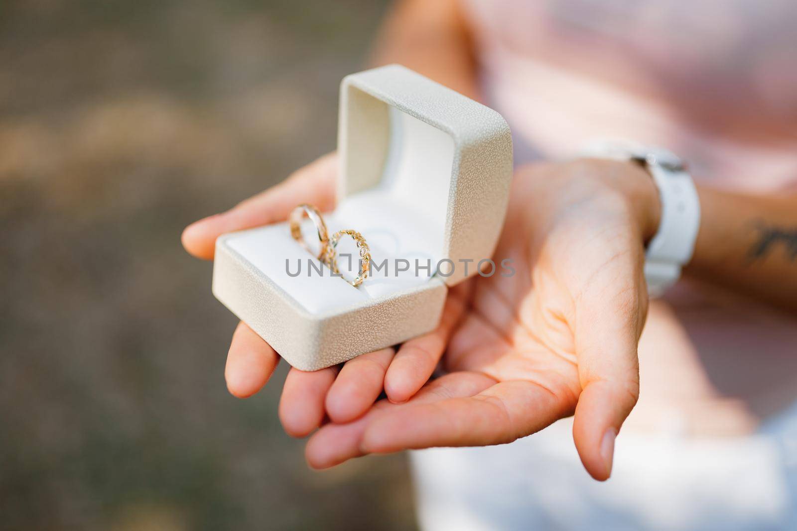Woman holding a white box with gold wedding rings in her hands, close-up . High quality photo