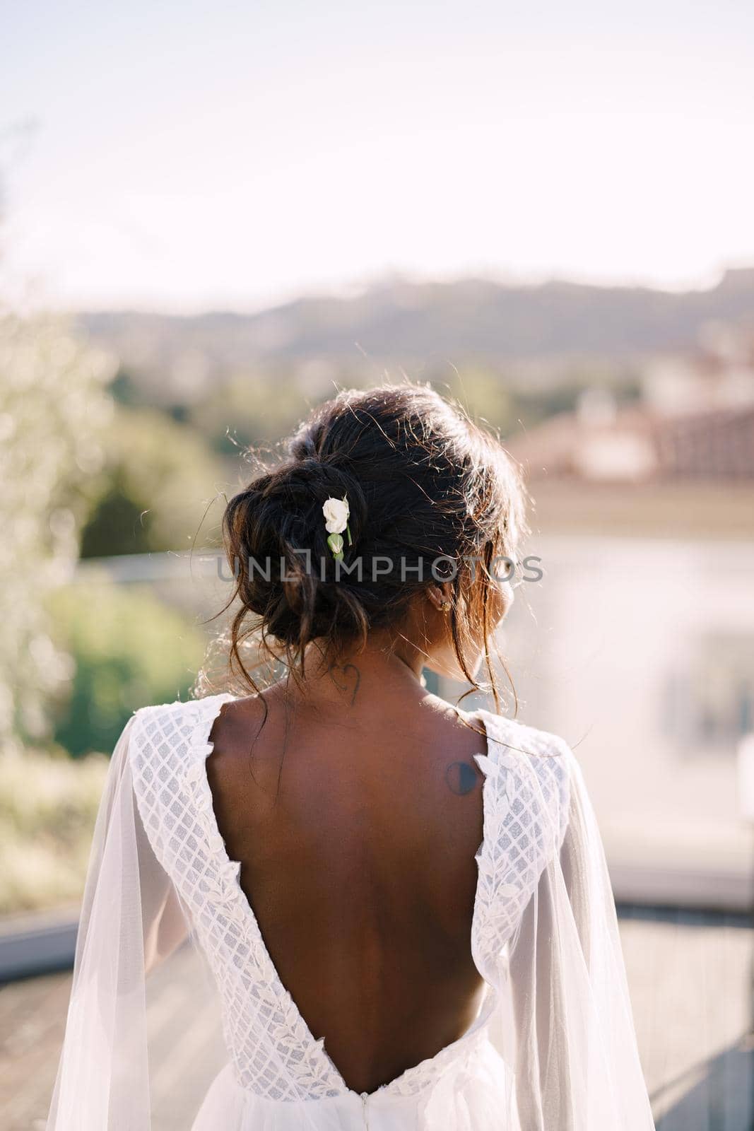 Destination fine-art wedding in Florence, Italy. The African-American bride stands with her back, in a white dress with a large neckline against the backdrop of Florence's urban landscape.