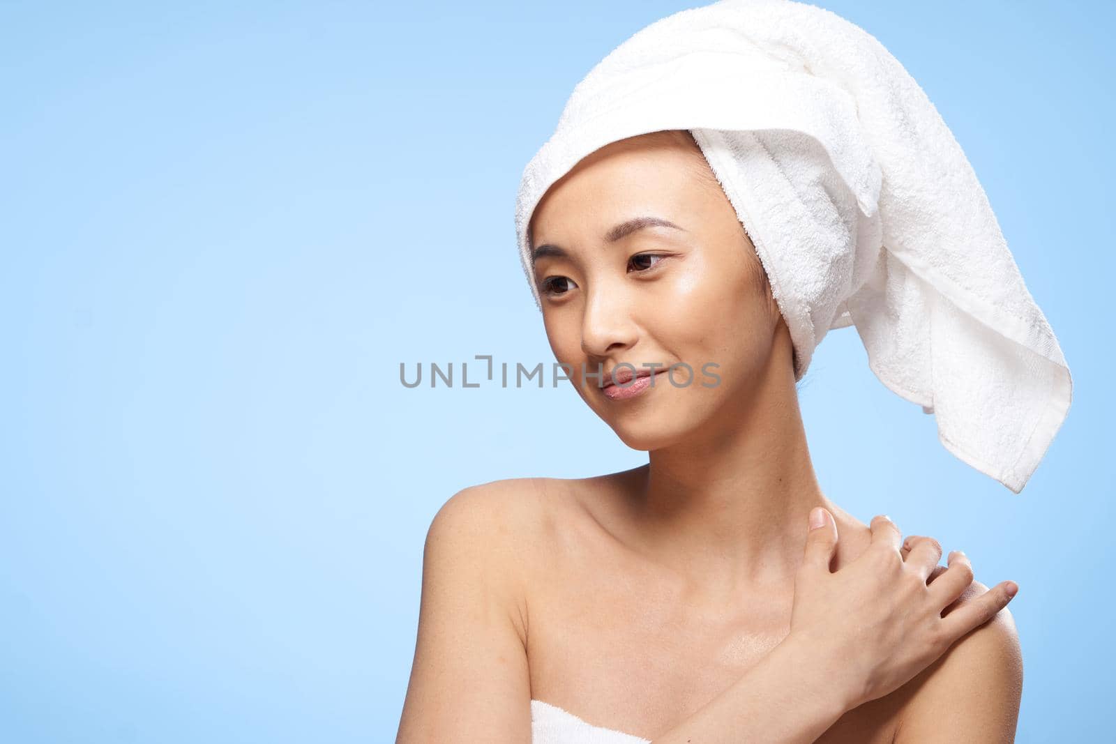 pretty asian woman clean skin care towel on head blue background. High quality photo