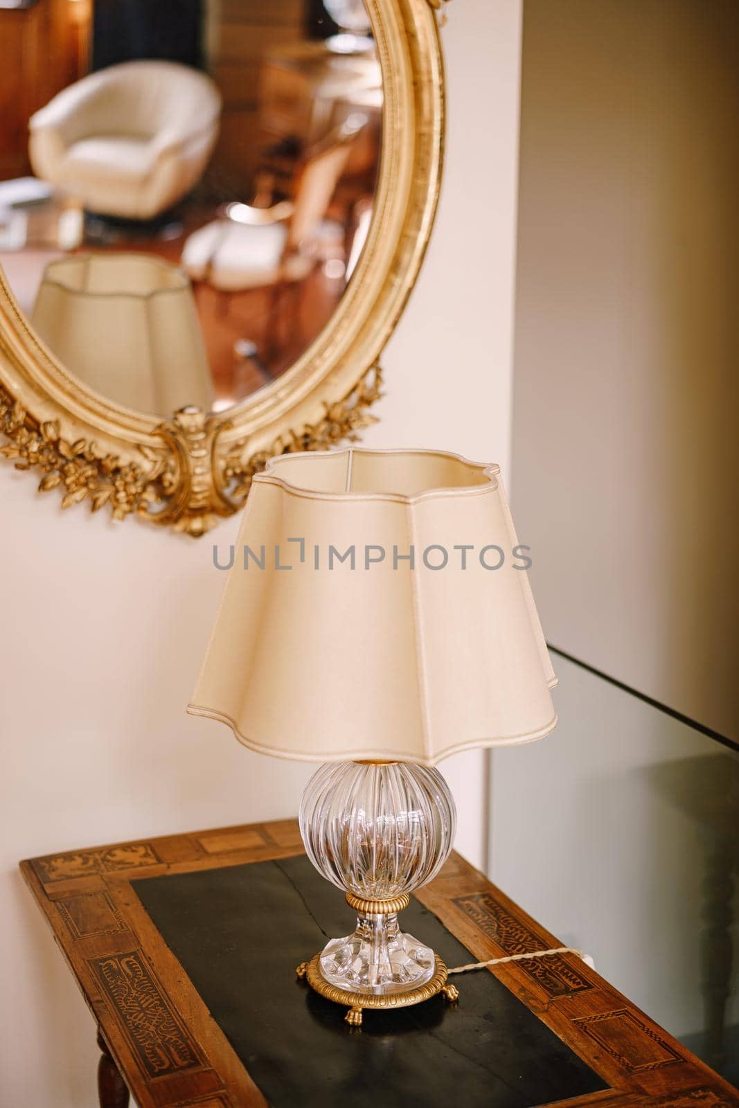 Vintage vintage table lamp with white lampshade and crystal base. An old mirror in a golden frame.
