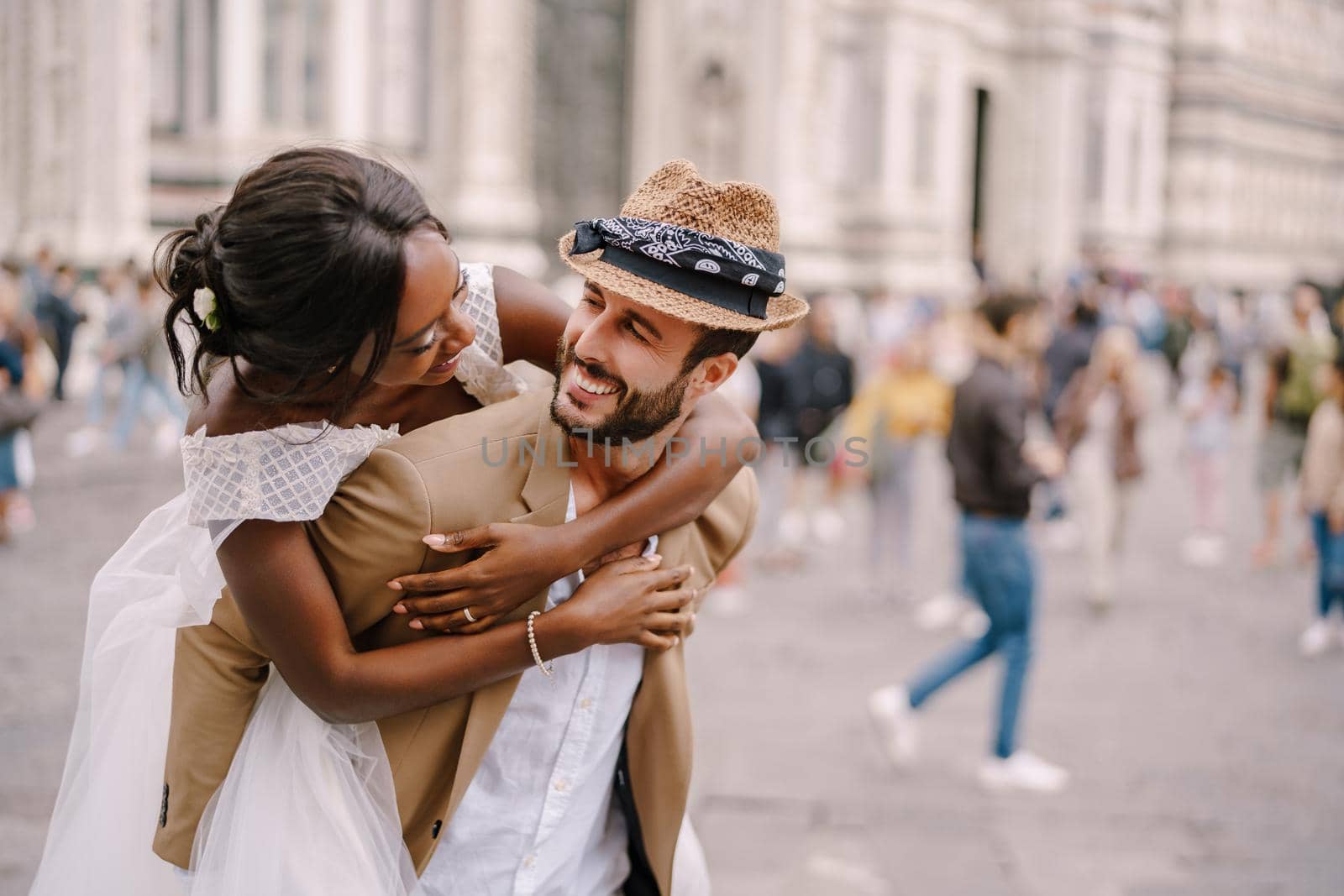 Multiethnic wedding couple. Wedding in Florence, Italy. African-American bride hugs from behind a Caucasian groom. by Nadtochiy