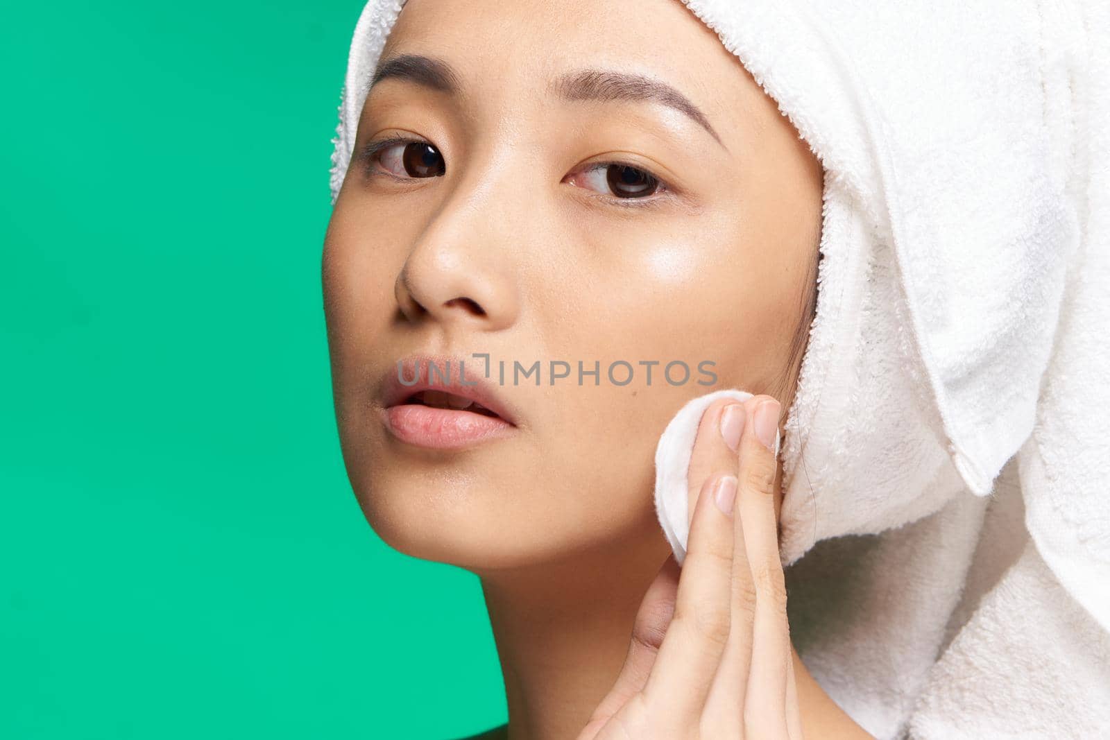 pretty asian woman bare shoulders towel on head cotton pad clean skin green background. High quality photo