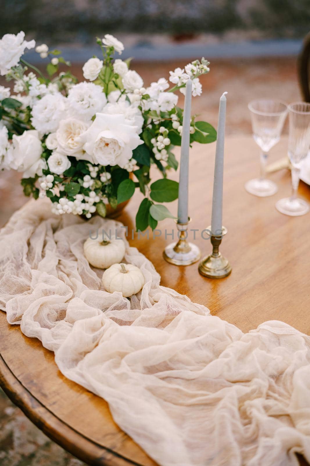 A close-up of a wooden table decorated for a wedding dinner.