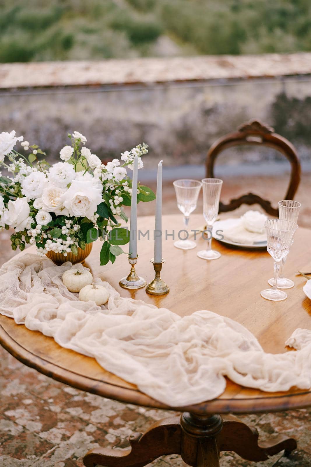 A close-up of a wooden table decorated for a wedding dinner.