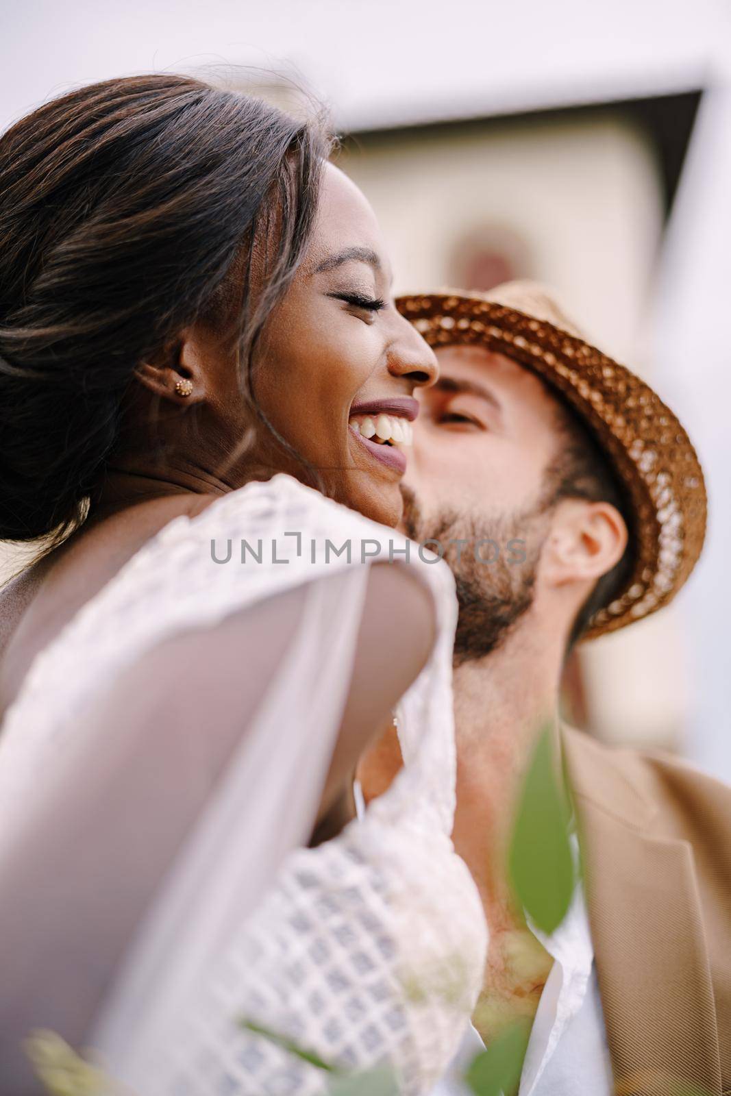 Multiracial wedding couple. Wedding in Florence, Italy. A close-up of portraits of an African-American bride and Caucasian groom in a straw hat. by Nadtochiy