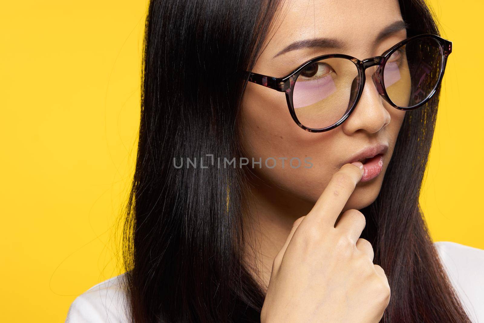 woman of asian appearance glasses attractive look holds finger on lips. High quality photo