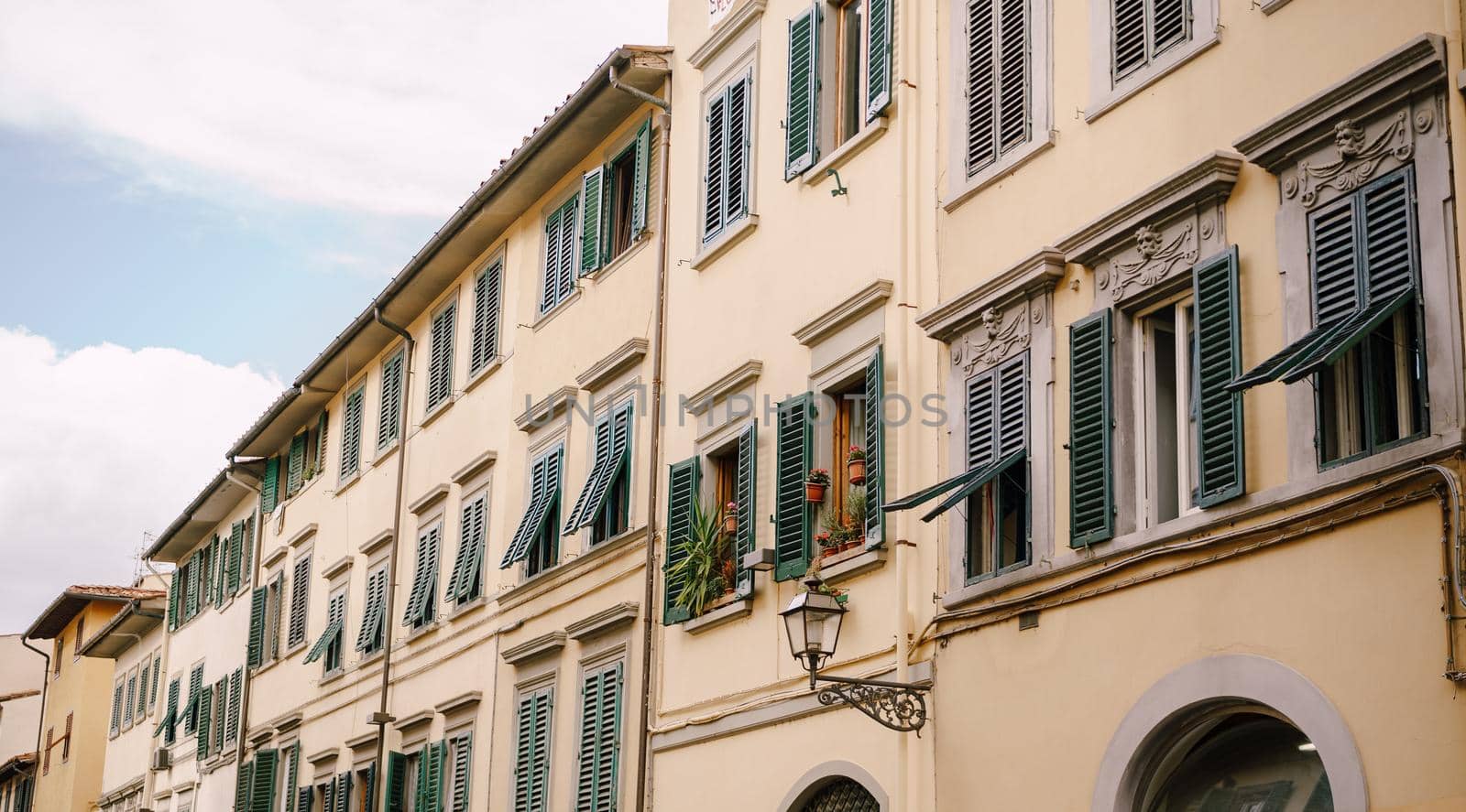Facade of a residential building in Florence, Italy, with green wooden shutters.