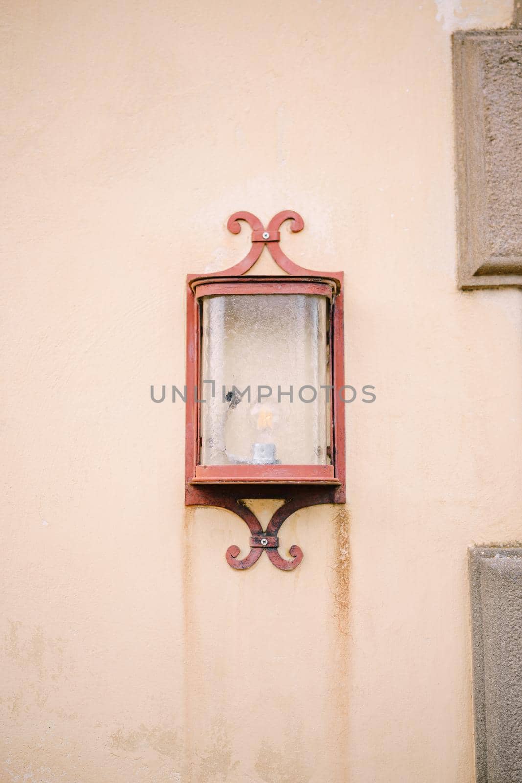 An ancient street lamp on a sand-colored wall.