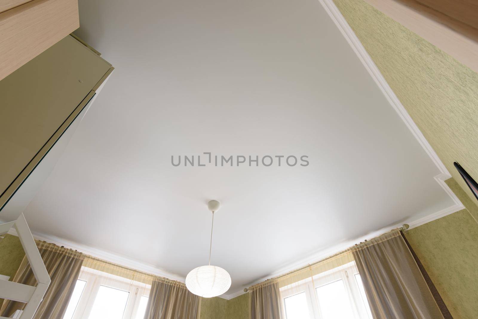 Stretch white matte ceiling close-up with a chandelier in the interior of a living bedroom by Madhourse